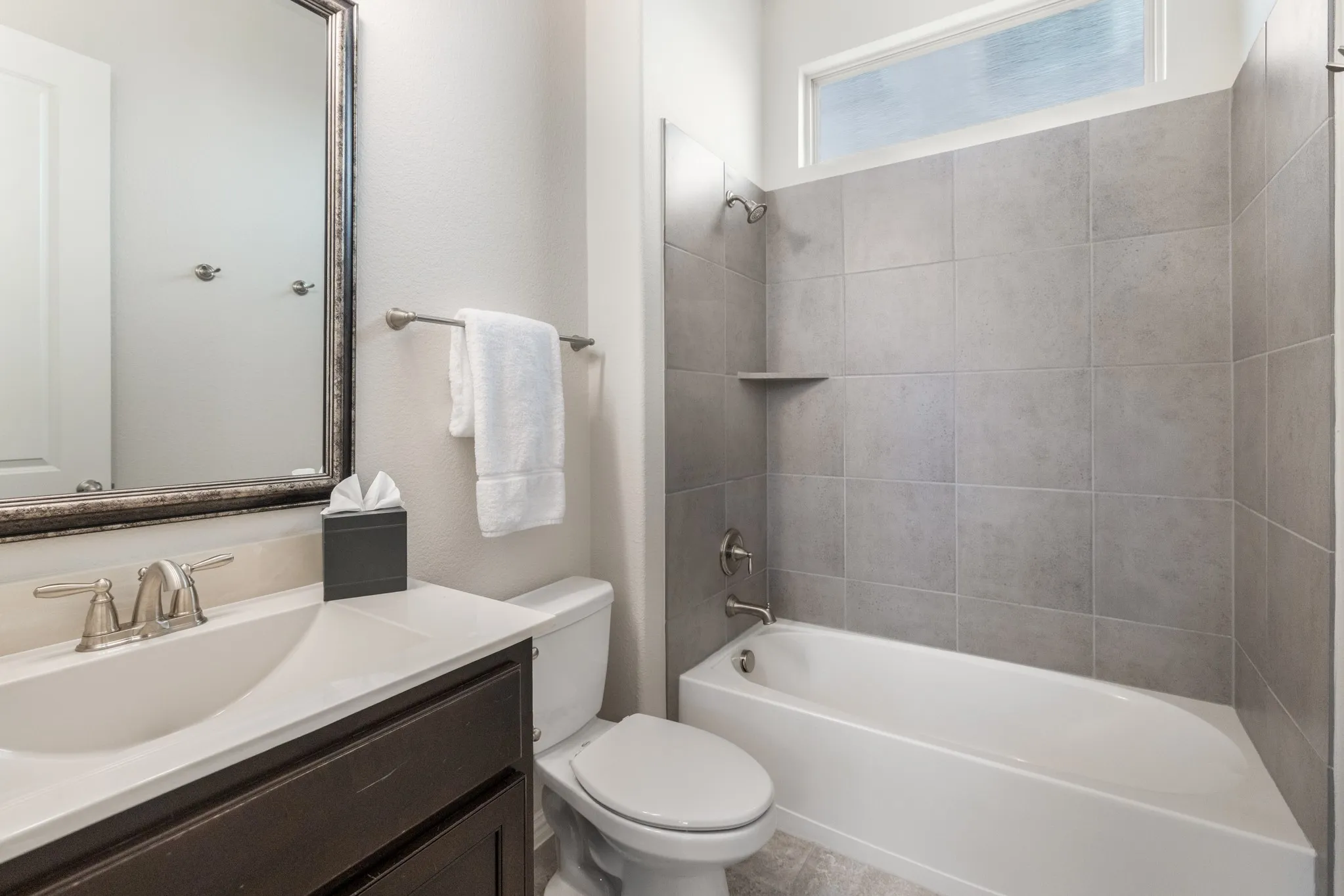 Downstairs bathroom with a dark wood-finish vanity, white countertop, and brushed nickel fixtures