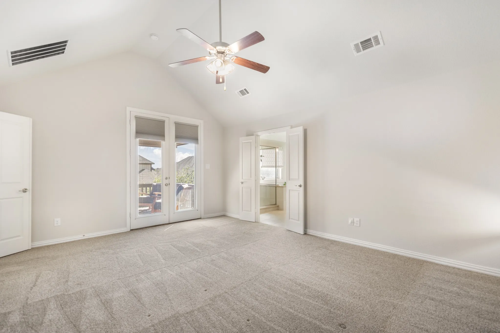 Vaulted ceiling with a ceiling fan, carpet flooring, double doors with exterior access, and additional interior door access