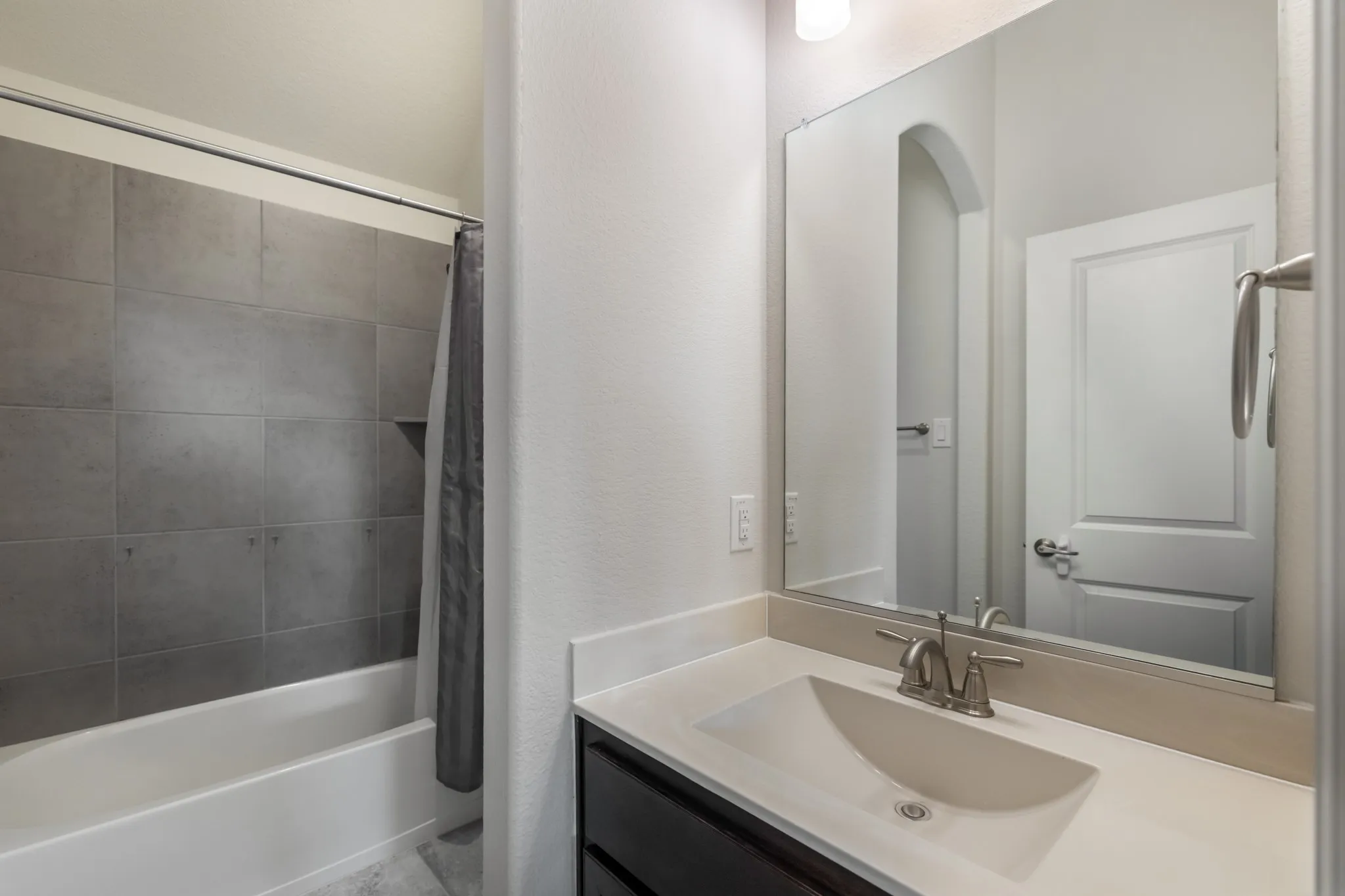 Upstairs jack and jill bathroom with tub and shower combination with grey tile surround and built-in niche