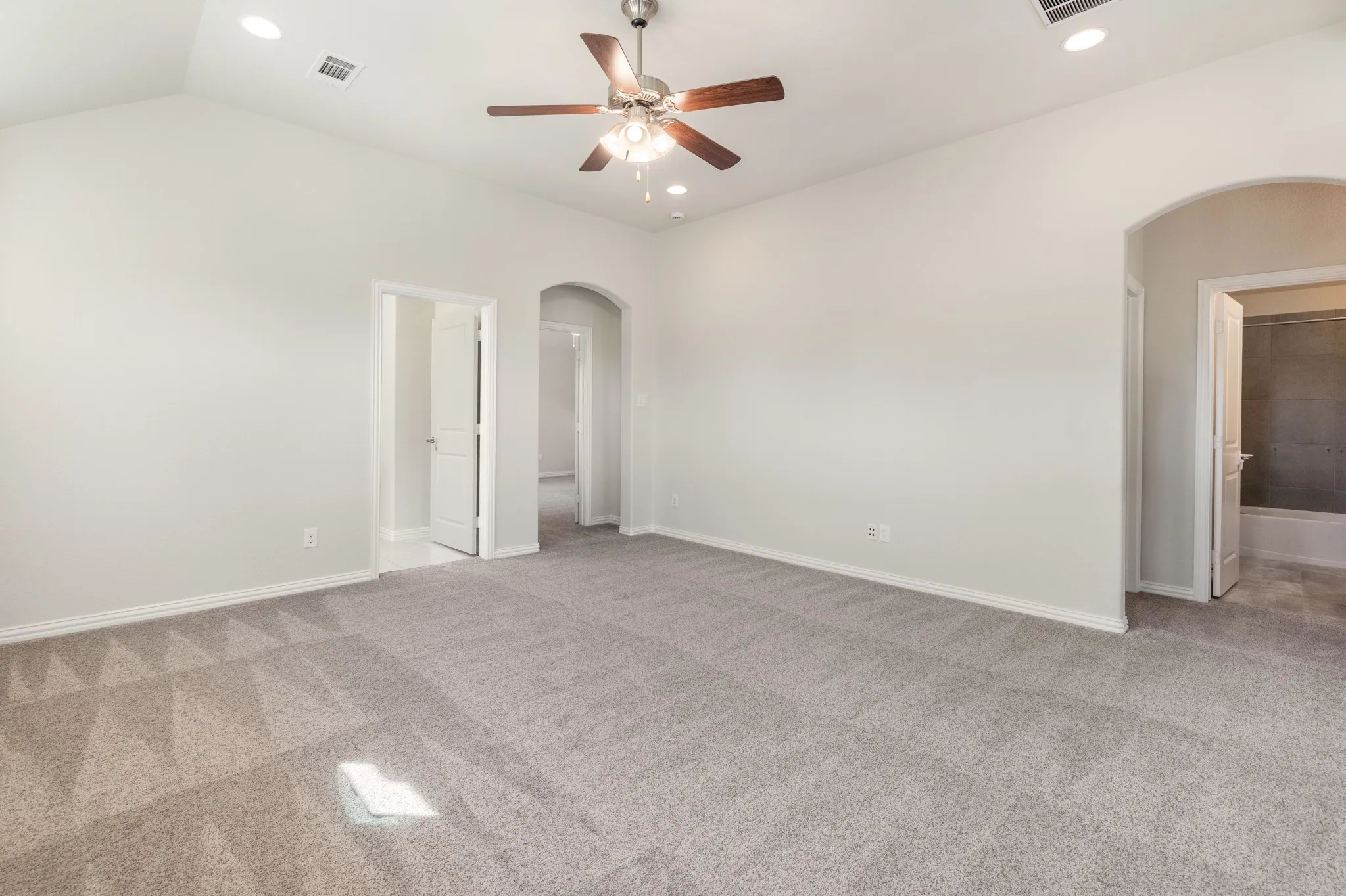 Upstairs family room with vaulted ceiling with a ceiling fan and recessed lighting, arched doorway