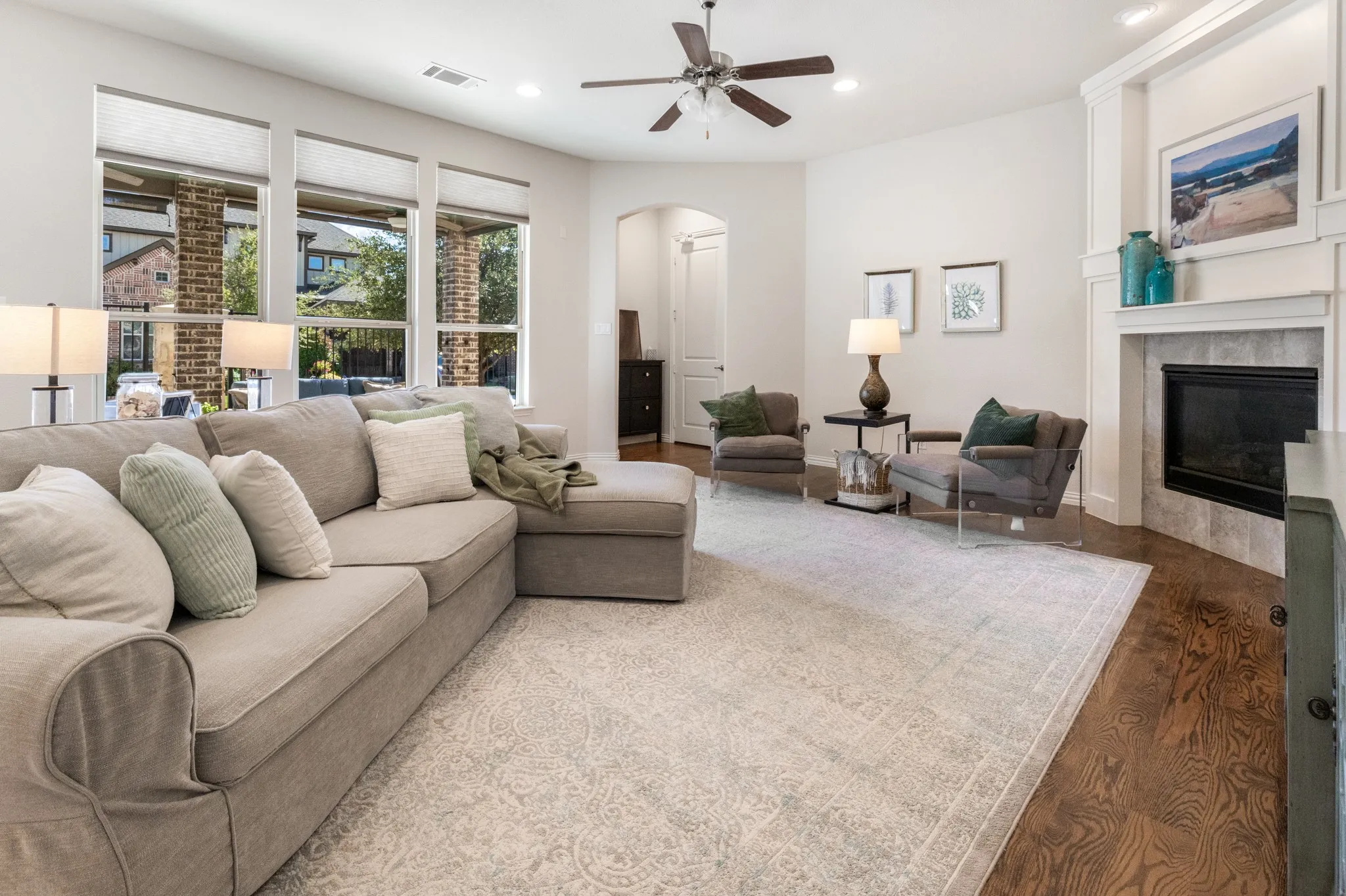Wood-finish flooring with a fireplace featuring a tiled surround and mantel