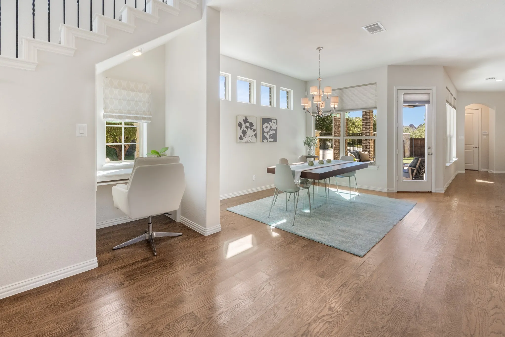 Built-in desk area with a window, wood-finish flooring, dining area with chandelier, large windows, and a glass-paneled door