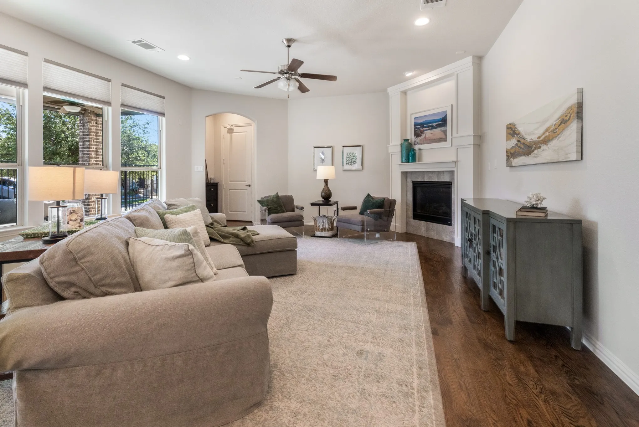 Hardwood flooring, recessed lighting, ceiling fan, corner fireplace with mantel, and large windows