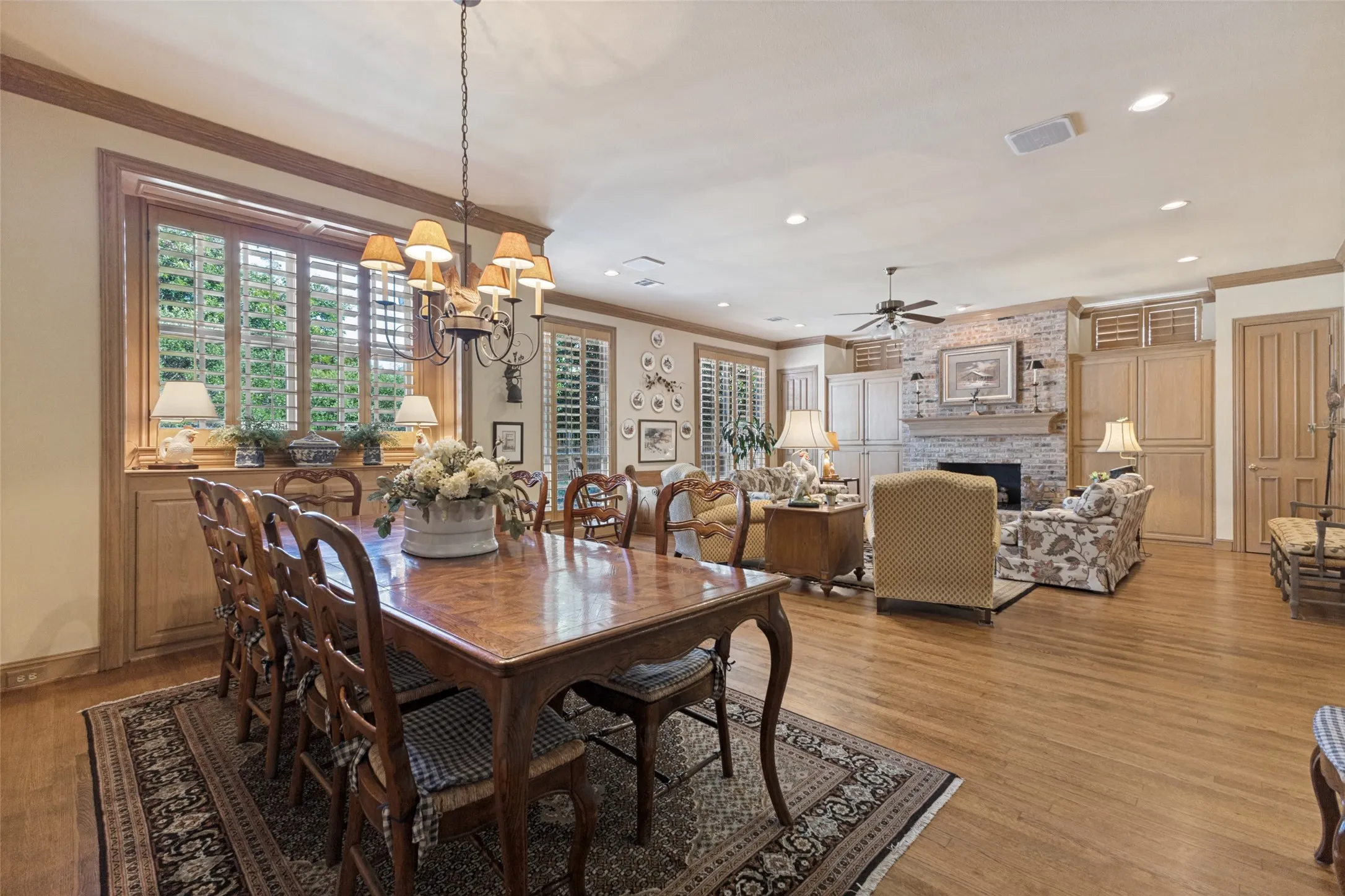 Wood-finish flooring throughout, custom wood cabinetry, fireplace with stone surround, crown molding, and plantation shutters