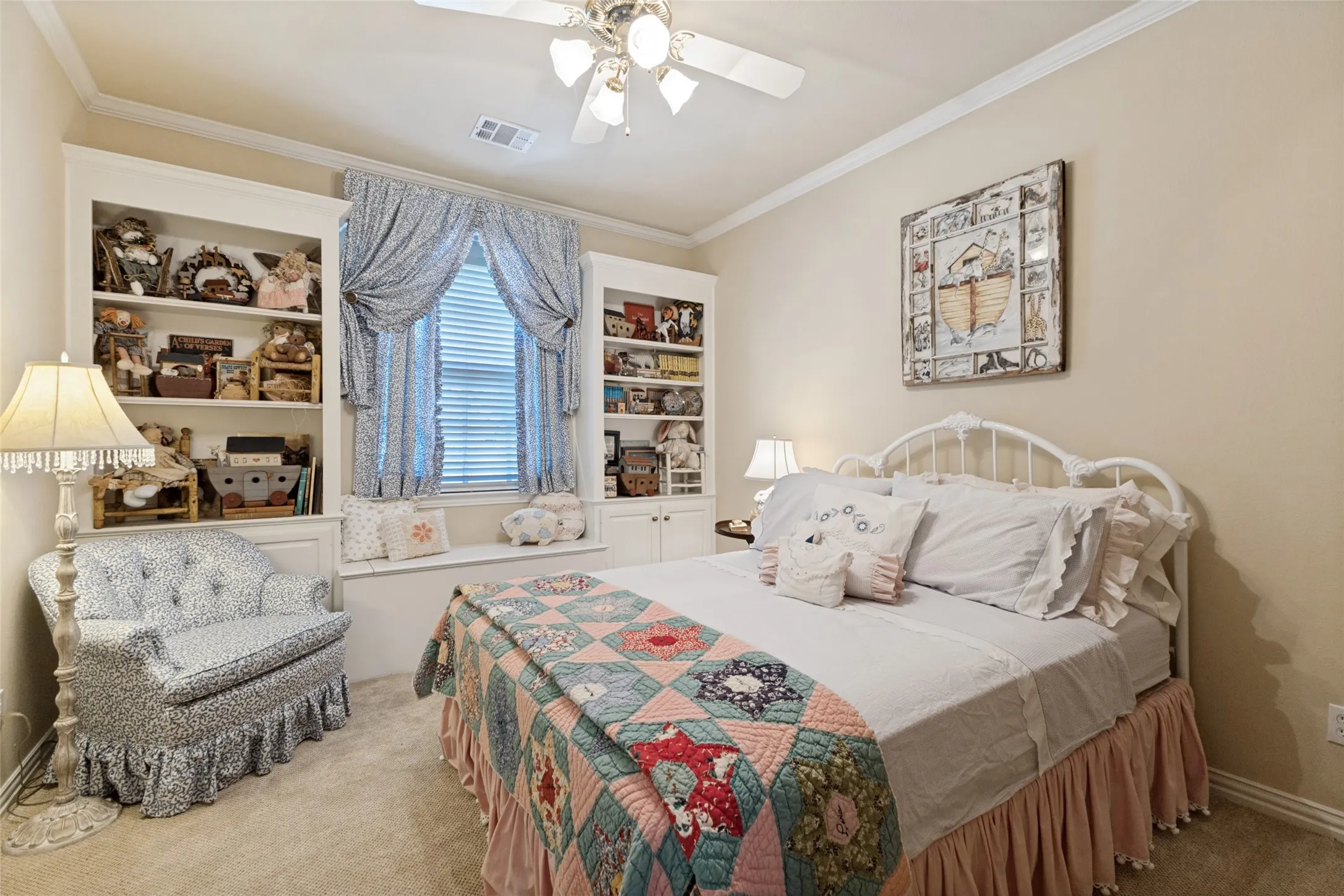 Built-in shelving flanking a window with a built-in bench, carpet flooring, a ceiling fan, and crown molding