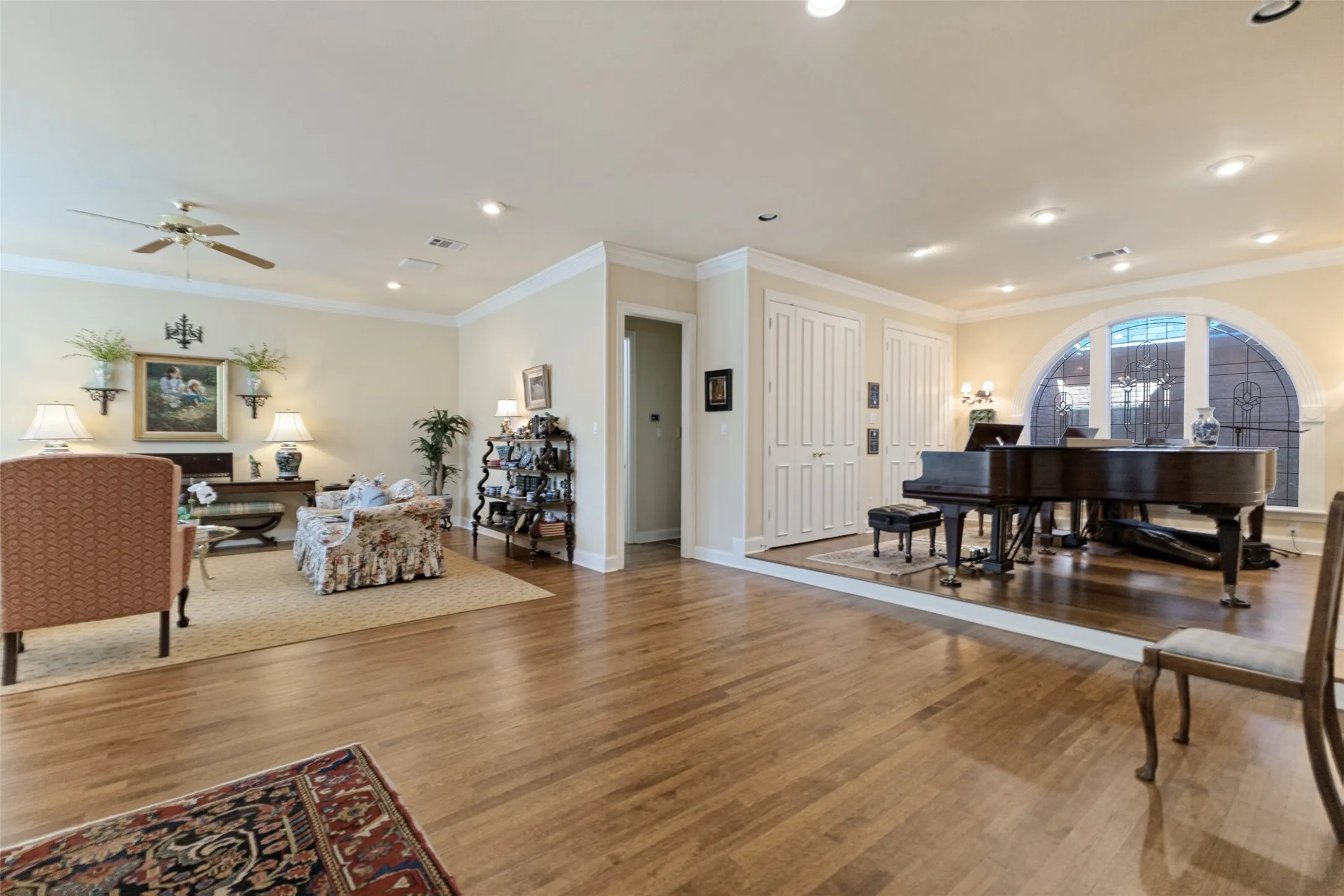 Hardwood flooring throughout, recessed lighting, crown molding, arched window with decorative grille, and built-in storage closets