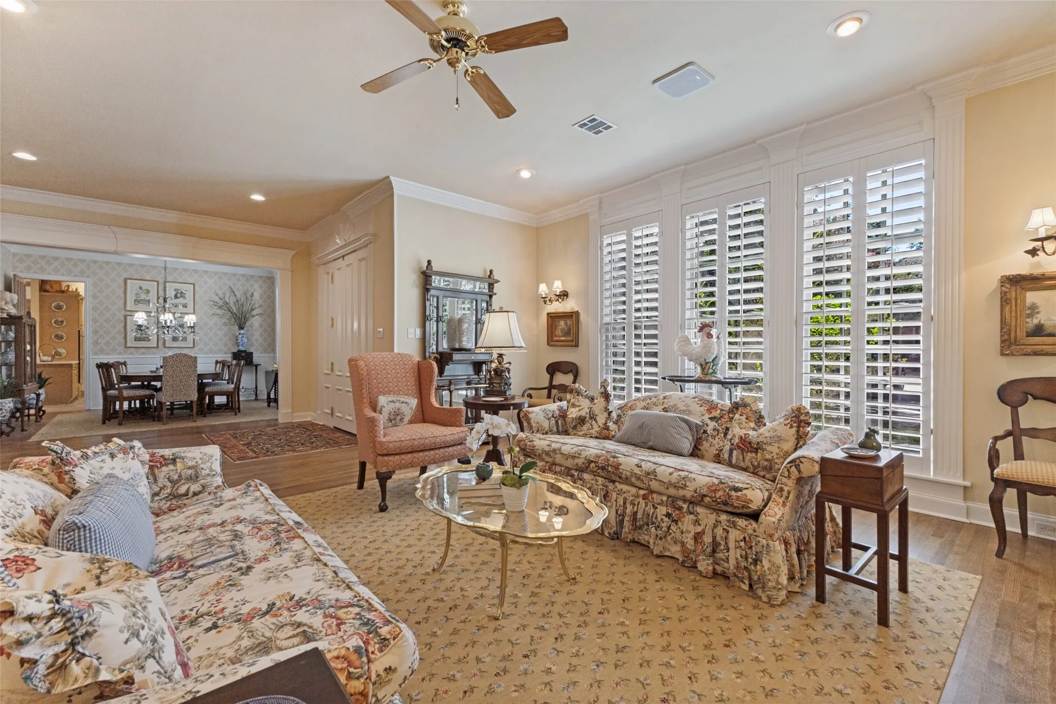 Recessed ceiling lighting, wood-finish flooring, ceiling fan, crown molding, and plantation shutters