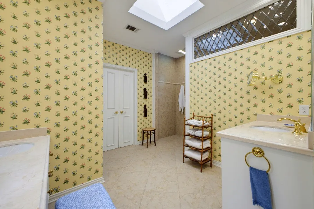 Dual vanities with integrated sinks, a skylight, tile flooring, and a leaded glass transom window