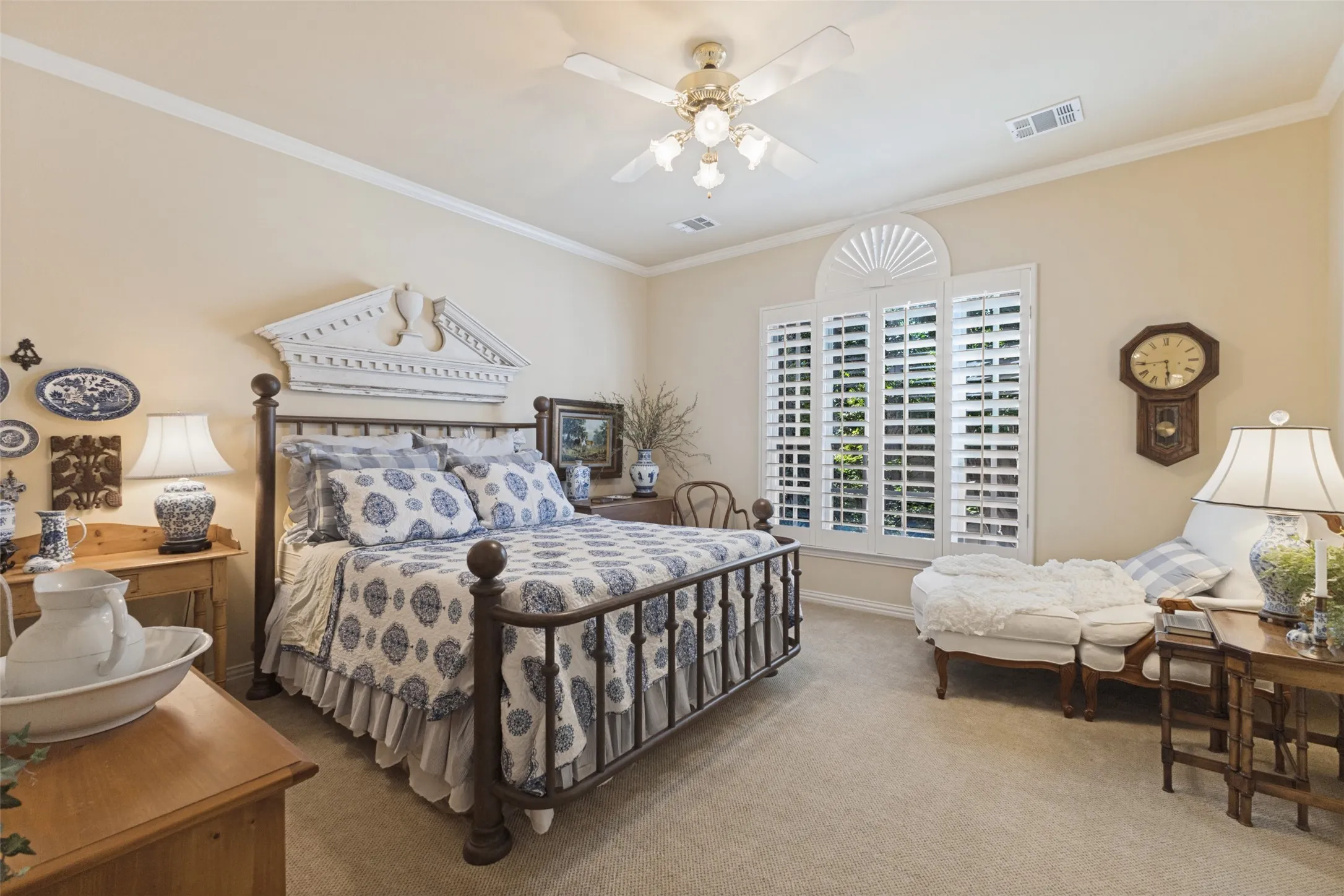 Carpeted room featuring a ceiling fan, crown molding, and windows with plantation shutters