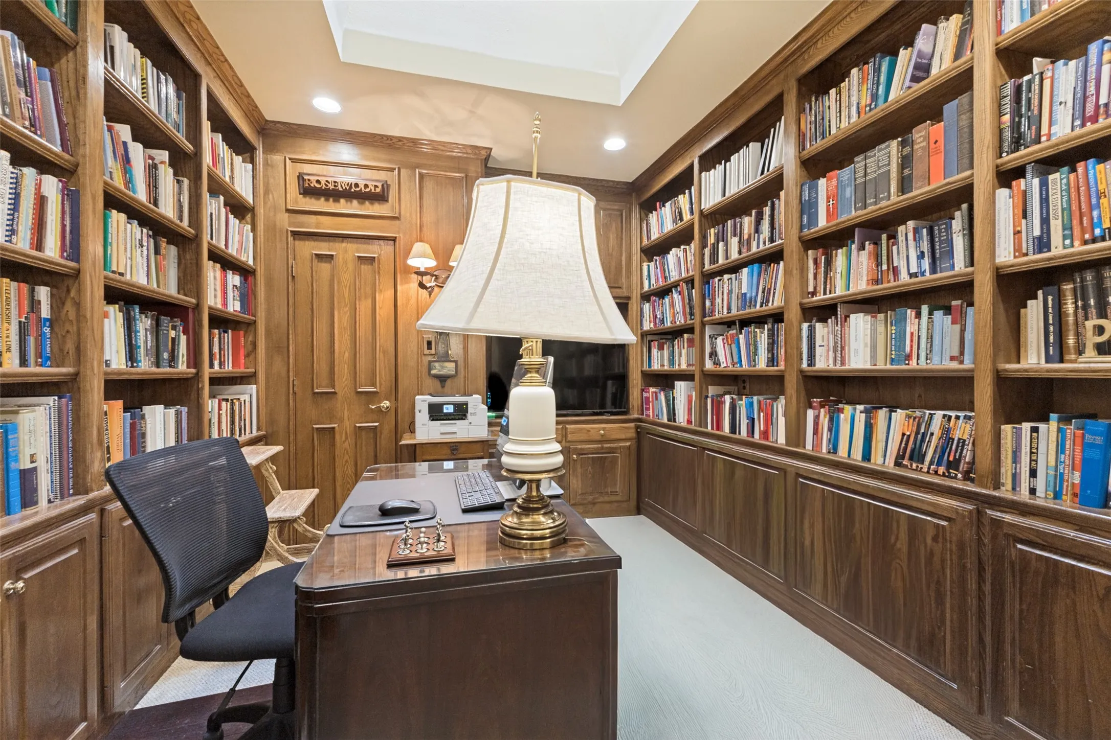 Built-in wood shelving and cabinetry with crown molding, wood paneling, and a recessed ceiling feature