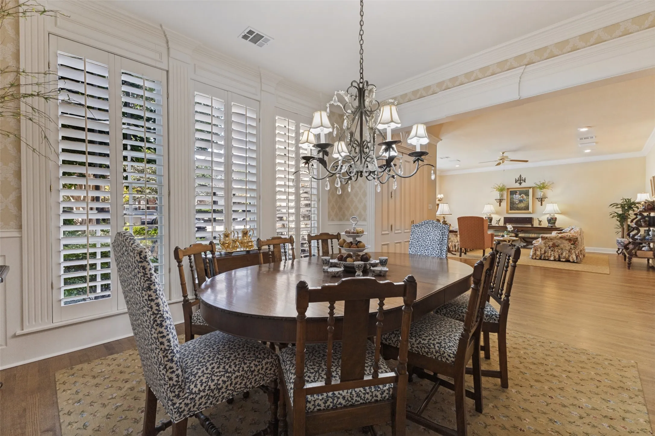 Expansive dining area featuring a chandelier, wood-finish flooring, and plantation shutters