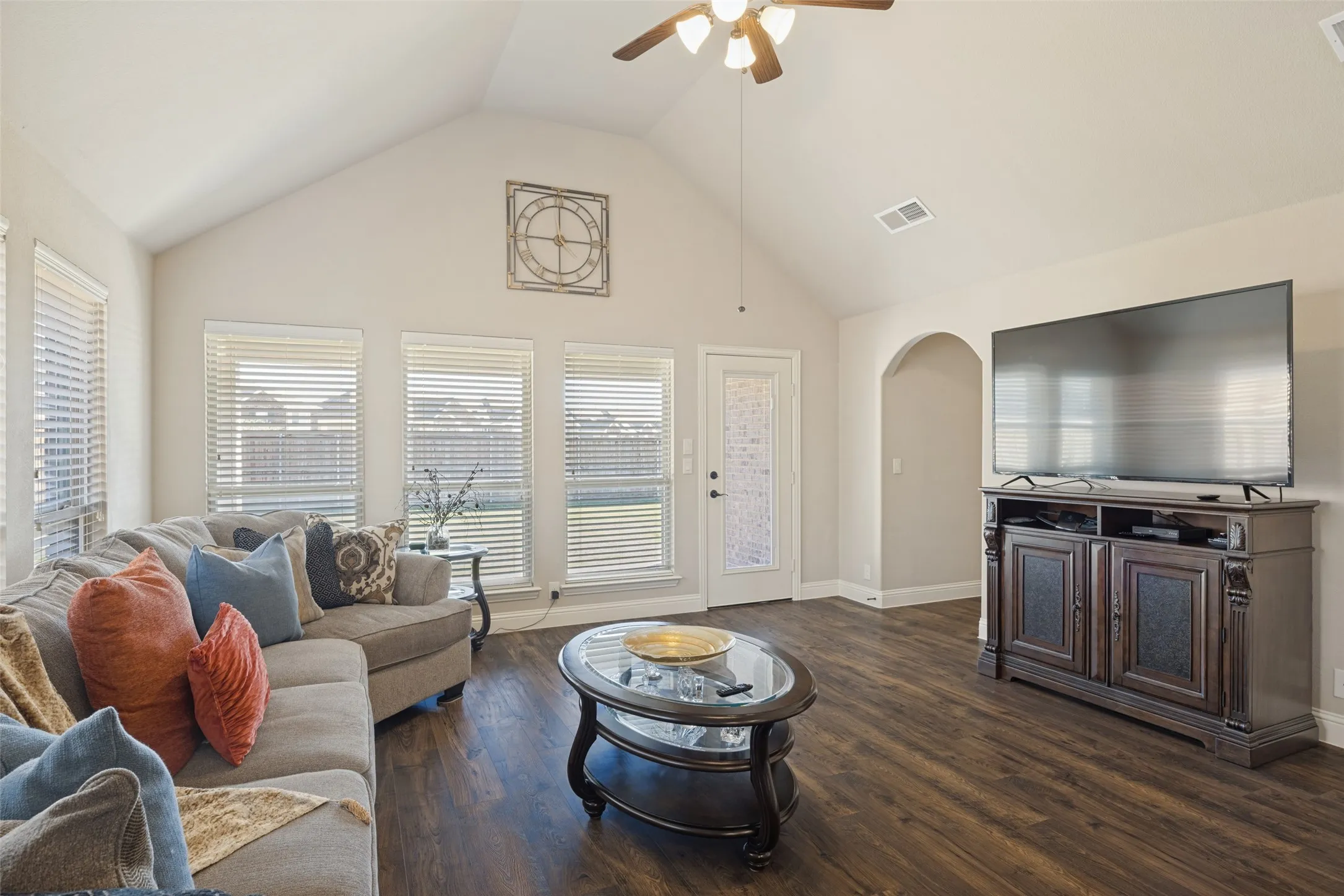 Another view of living area with ceiling fan, high ceilings, and beautiful Laminate flooring.