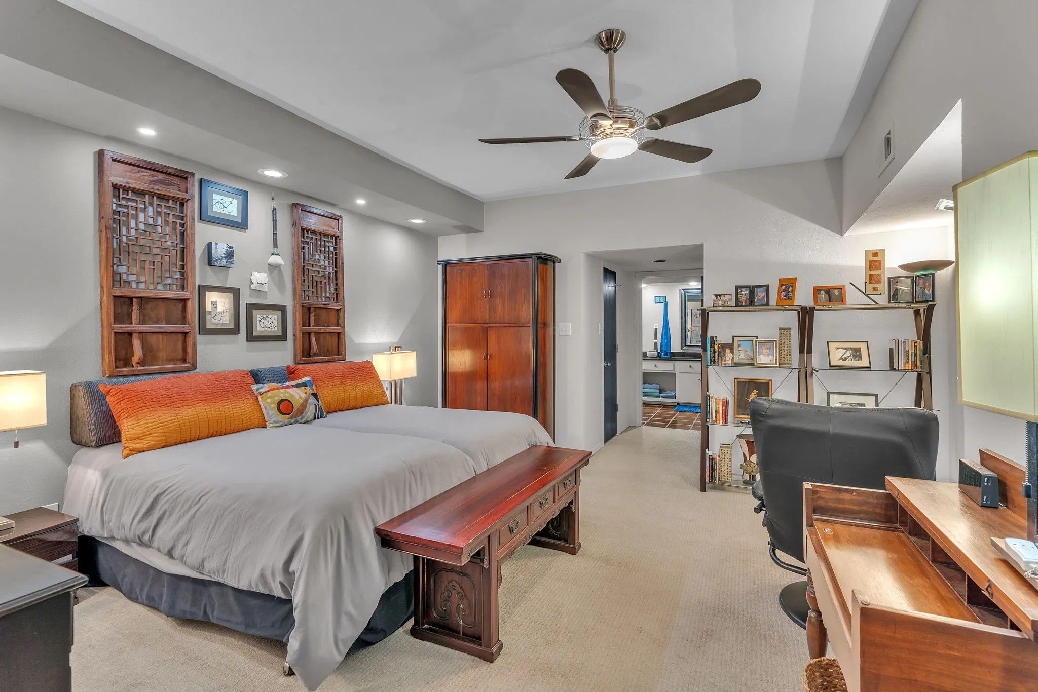 Large primary bedroom with sitting area, architectural ceiling fan, & carpet