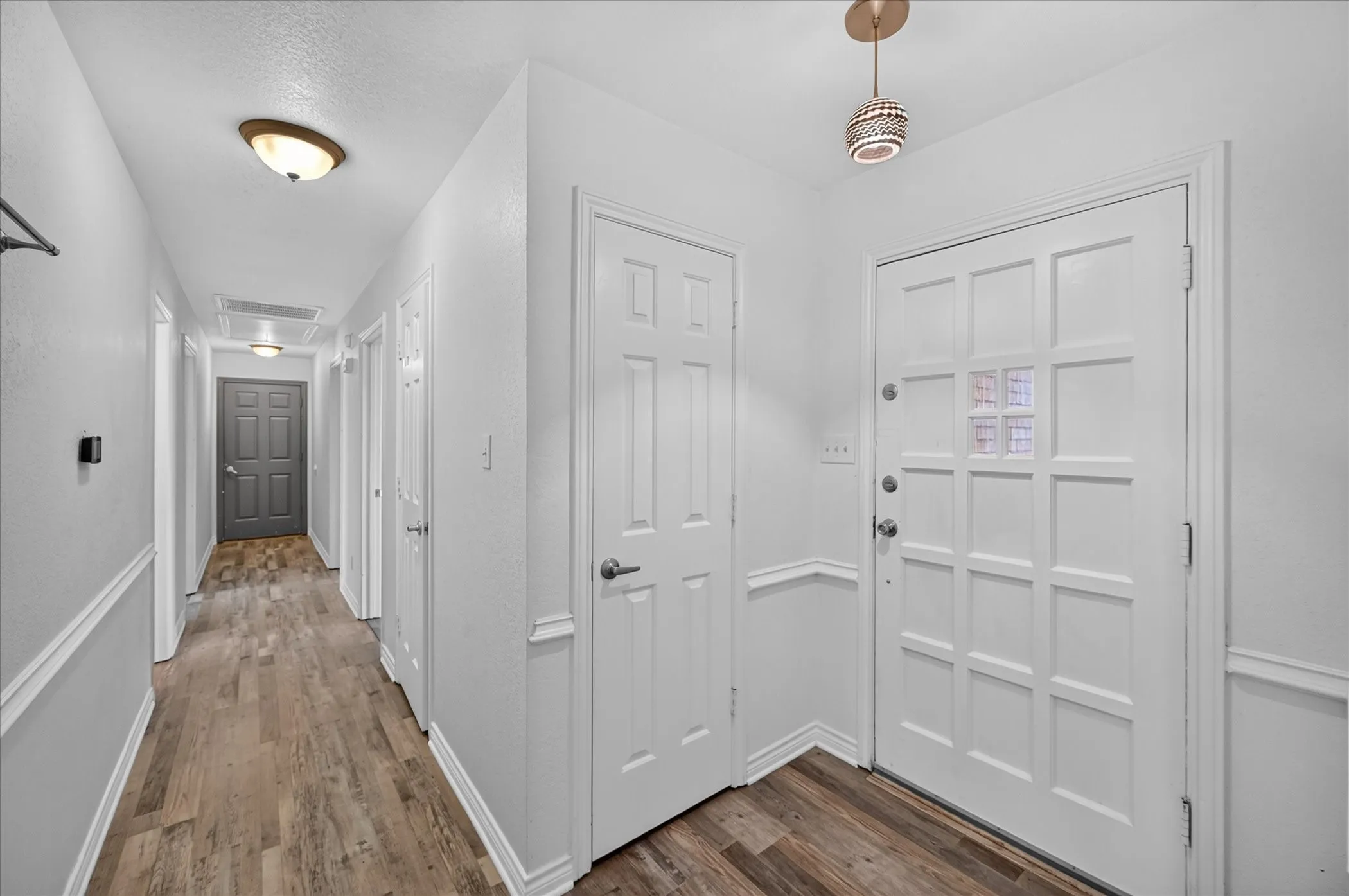 Entryway featuring wood-finish flooring, a white paneled entry door with frosted glass, and wainscoting