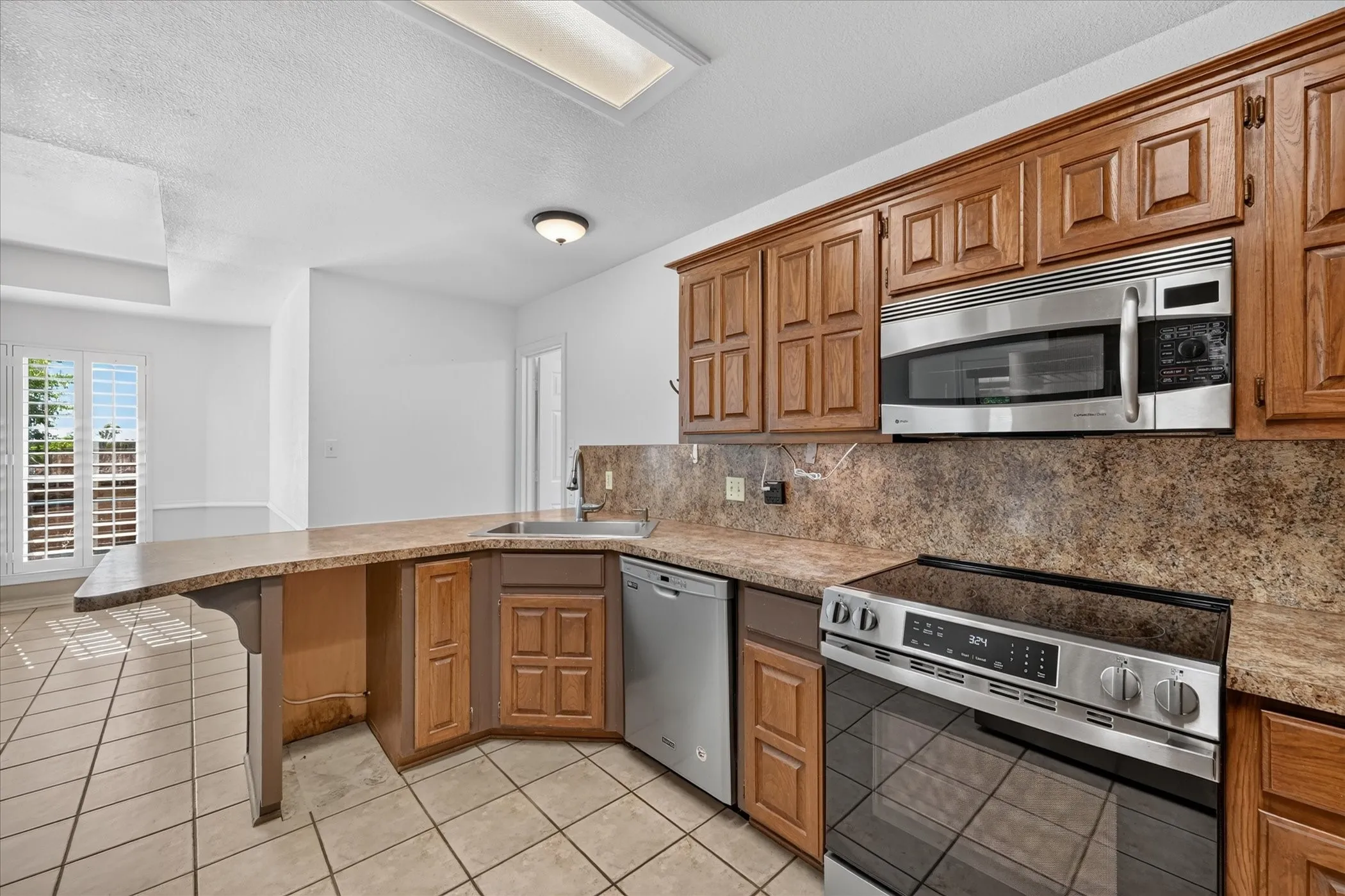 Kitchen featuring wood cabinetry, stainless steel appliances, a built-in microwave, and a tile backsplash