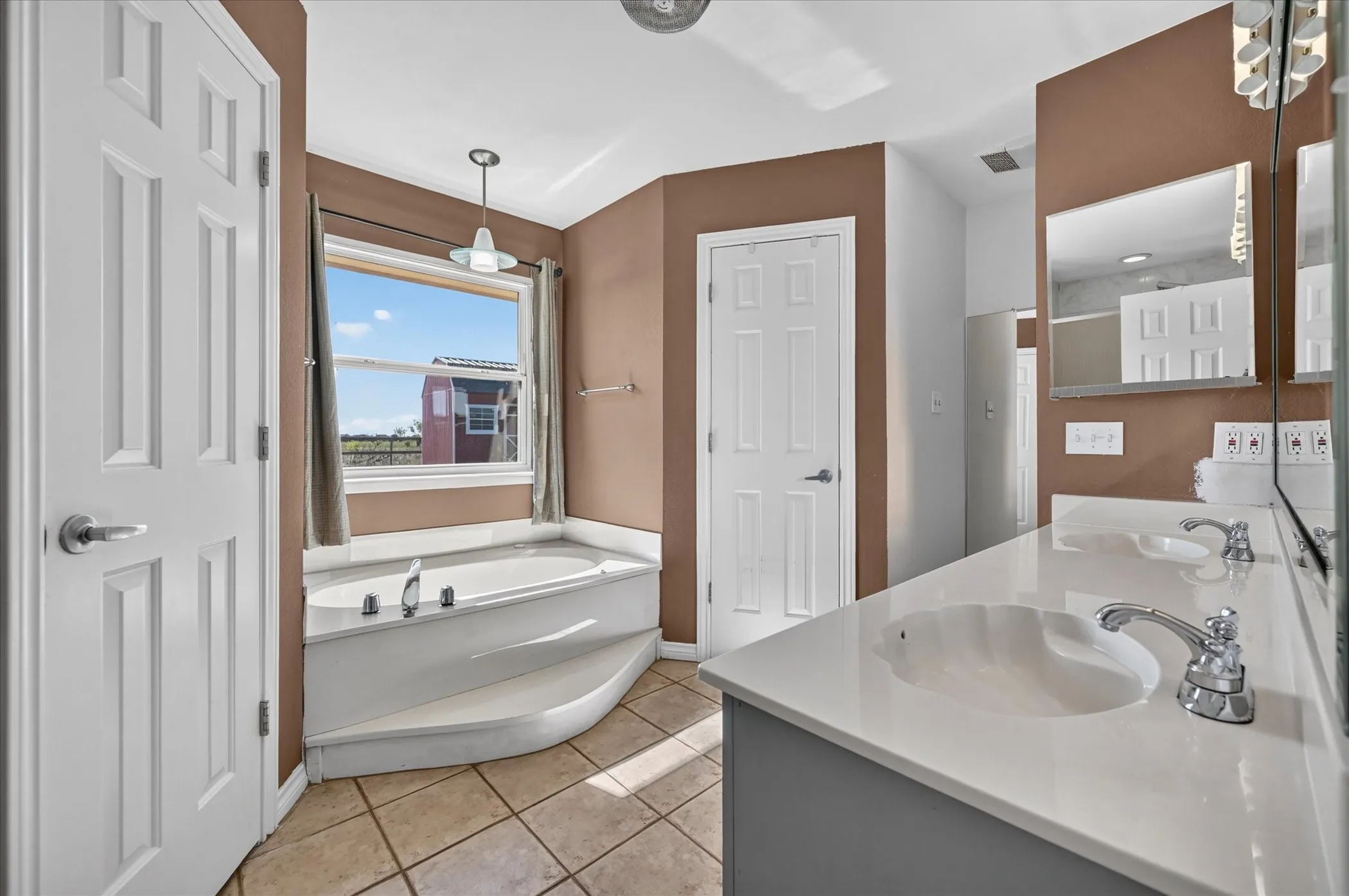 Dual vanity with integrated sinks, polished chrome fixtures, built-in soaking tub, his and her walk in closets, and tile flooring