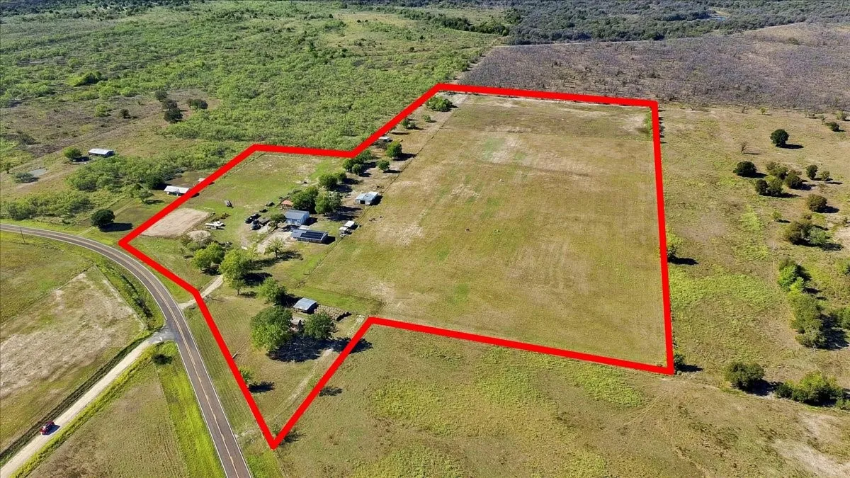 Expansive acreage featuring a substantial cleared field, multiple outbuildings, and direct road frontage
