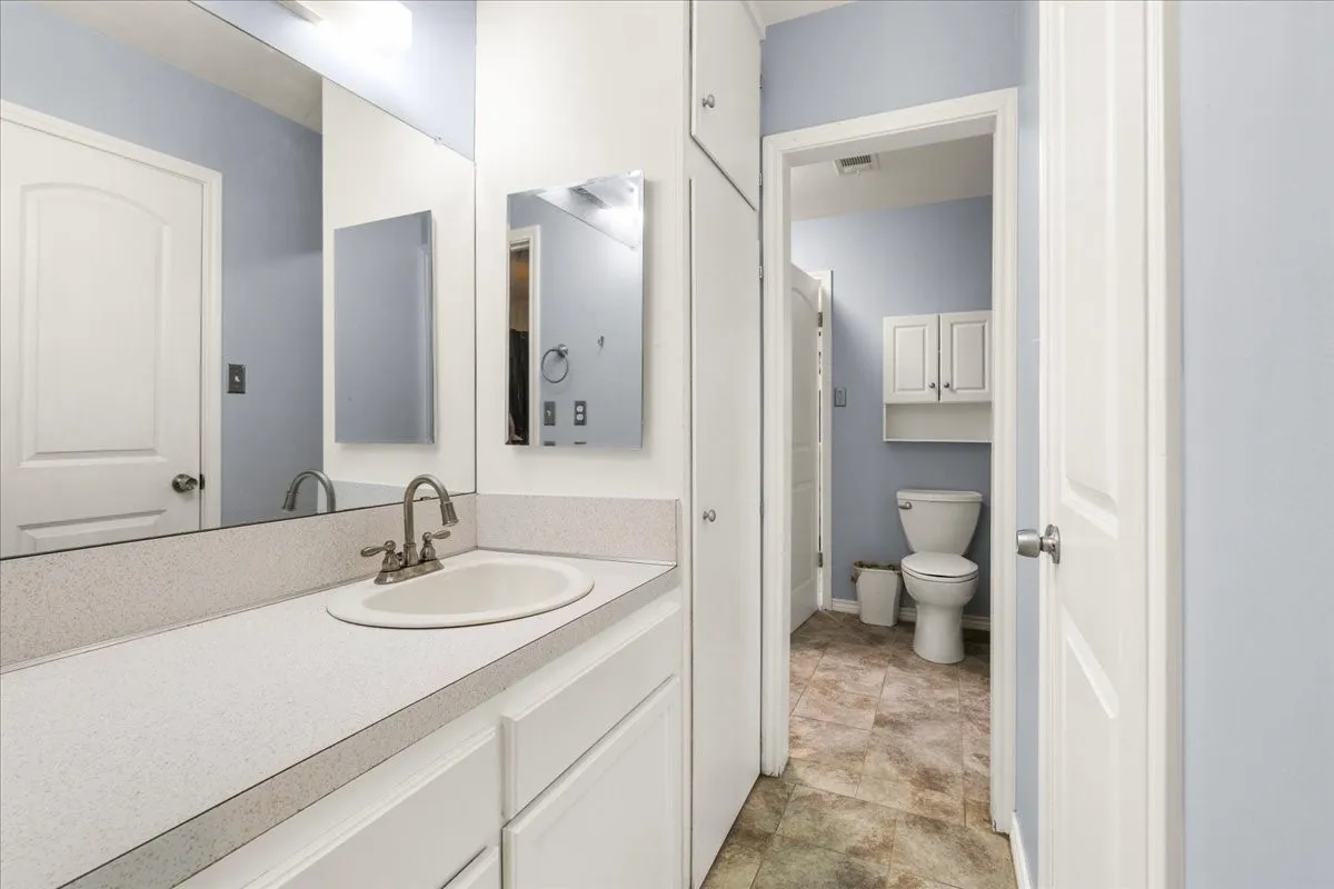 Vanity with integrated sink, dual-handle faucet, and white cabinetry