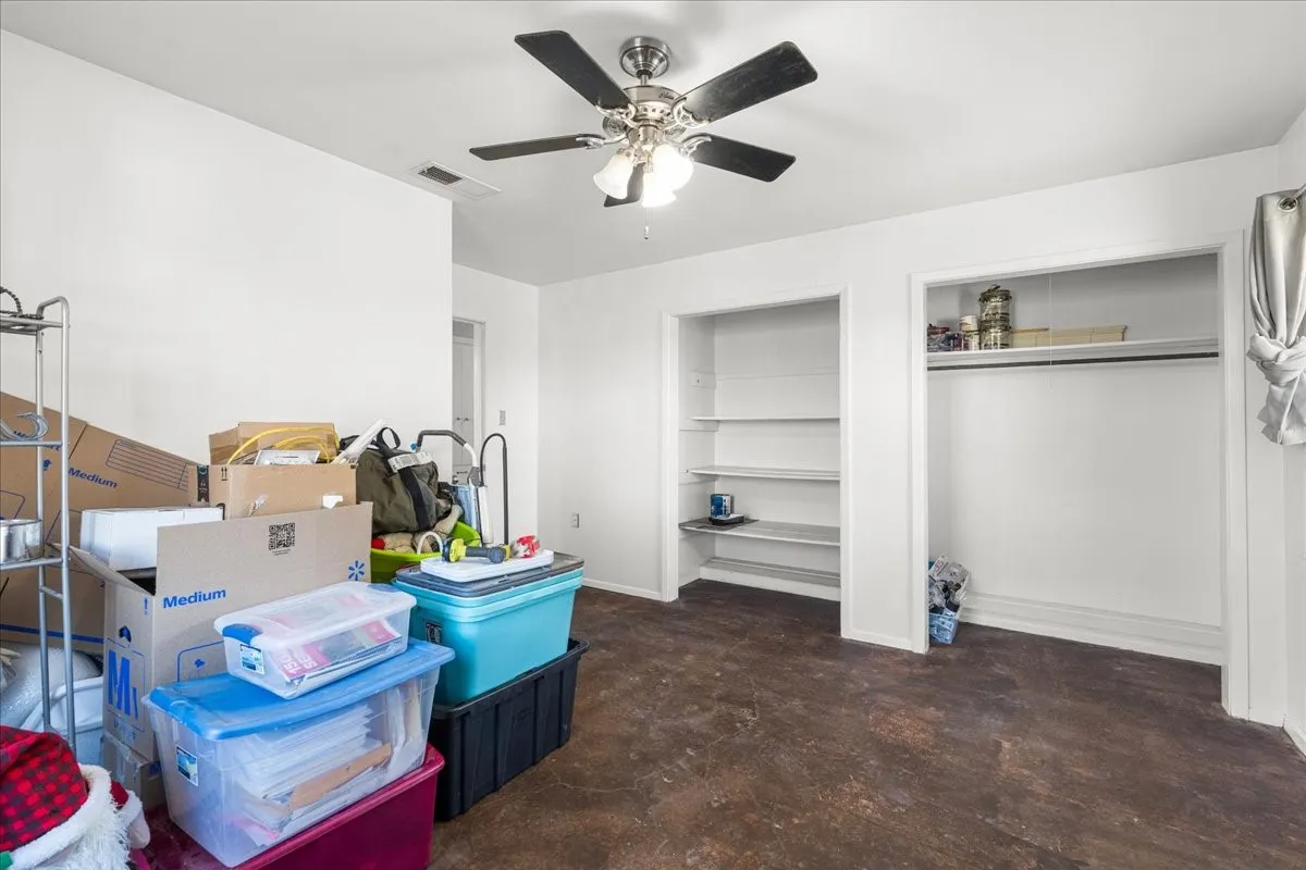 Ceiling fan light fixture, wood-finish flooring, built-in shelving, white walls, and a recessed air vent