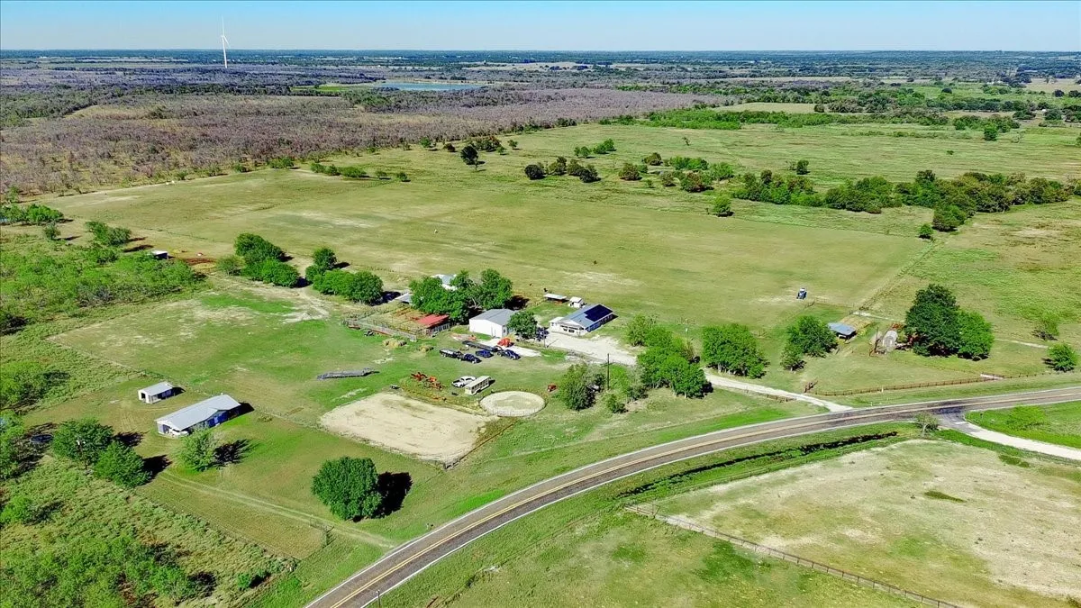 Expansive land parcel featuring multiple outbuildings, established structures, open fields, and a road frontage
