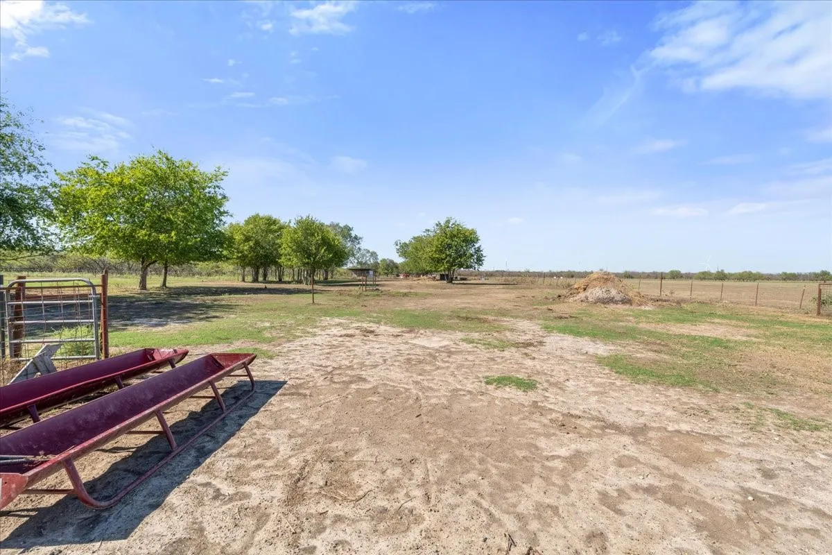 Expansive outdoor area featuring mature trees and a perimeter fence