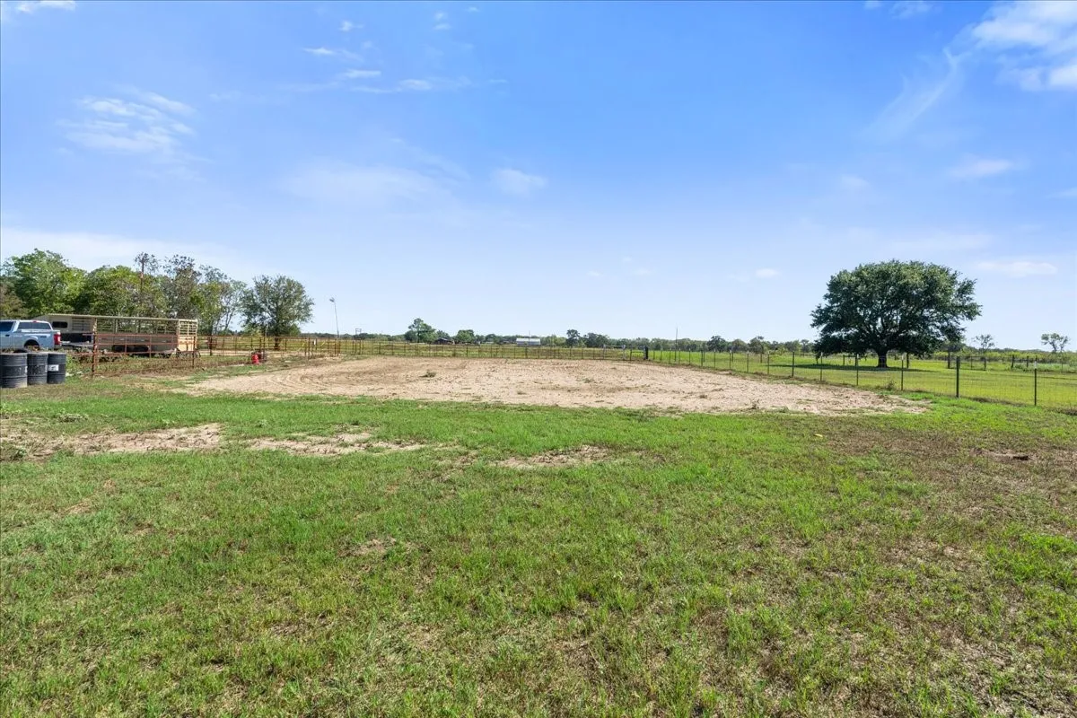 Expansive grassy area with a partial fence line and mature tree