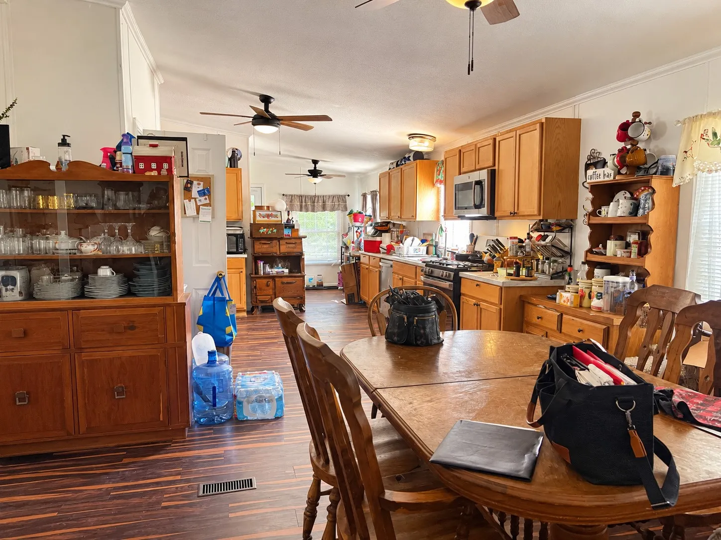 Expansive kitchen with wood-finish flooring, light wood cabinetry, stainless steel appliances, and ceiling fans