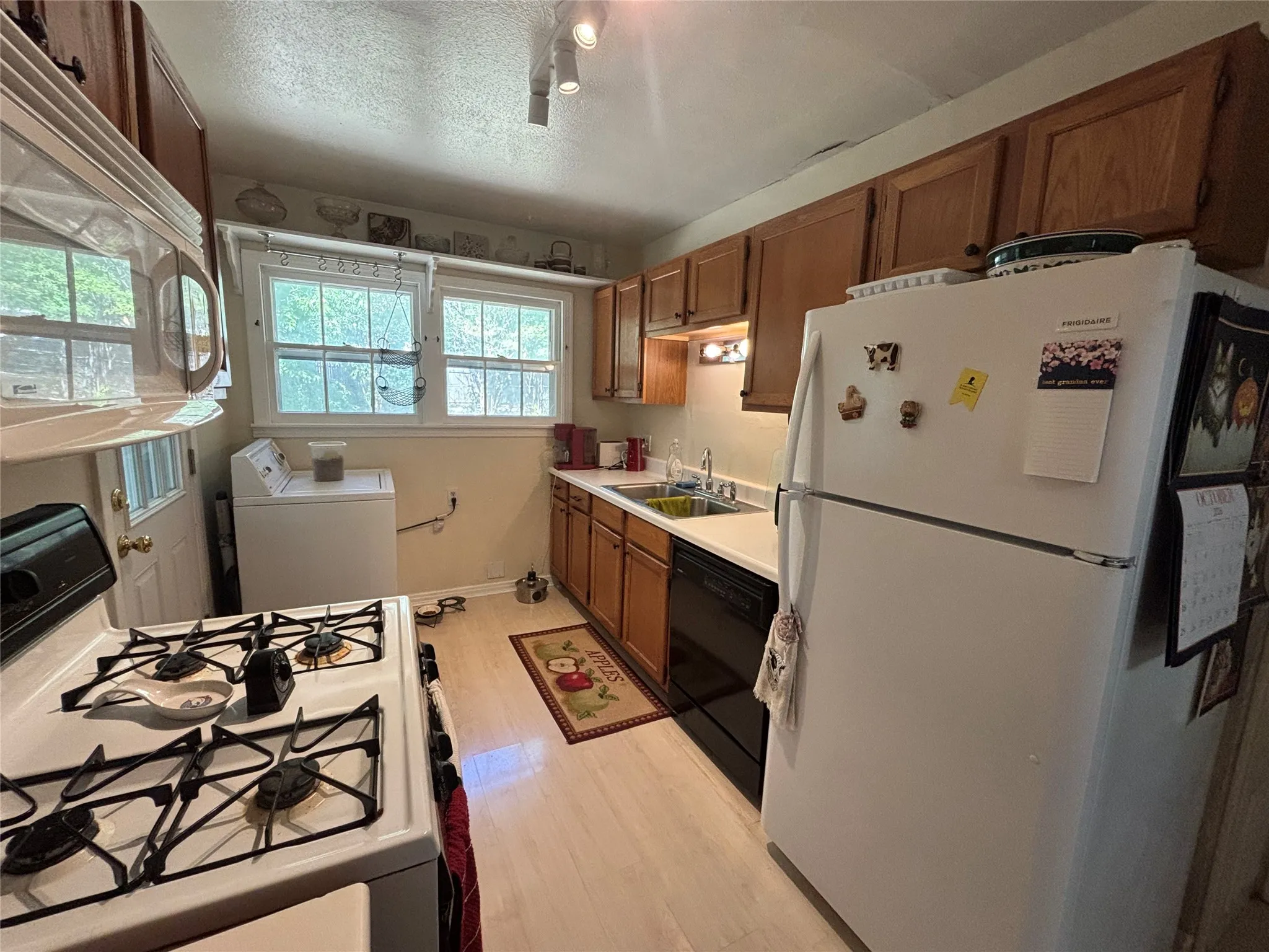 Full kitchen featuring wood-finish cabinetry, light-toned flooring, and a white gas range