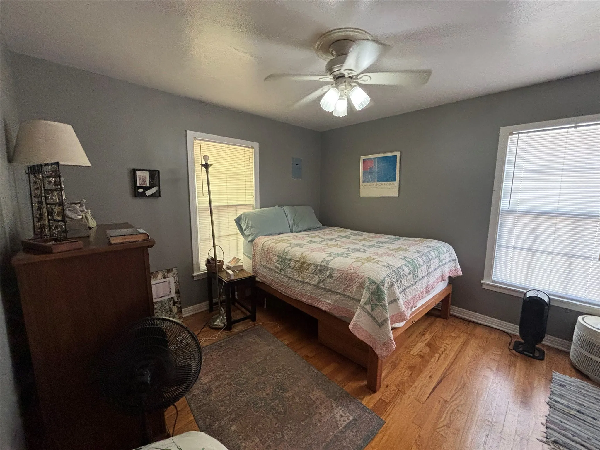 Hardwood flooring with a ceiling fan light fixture and multiple windows