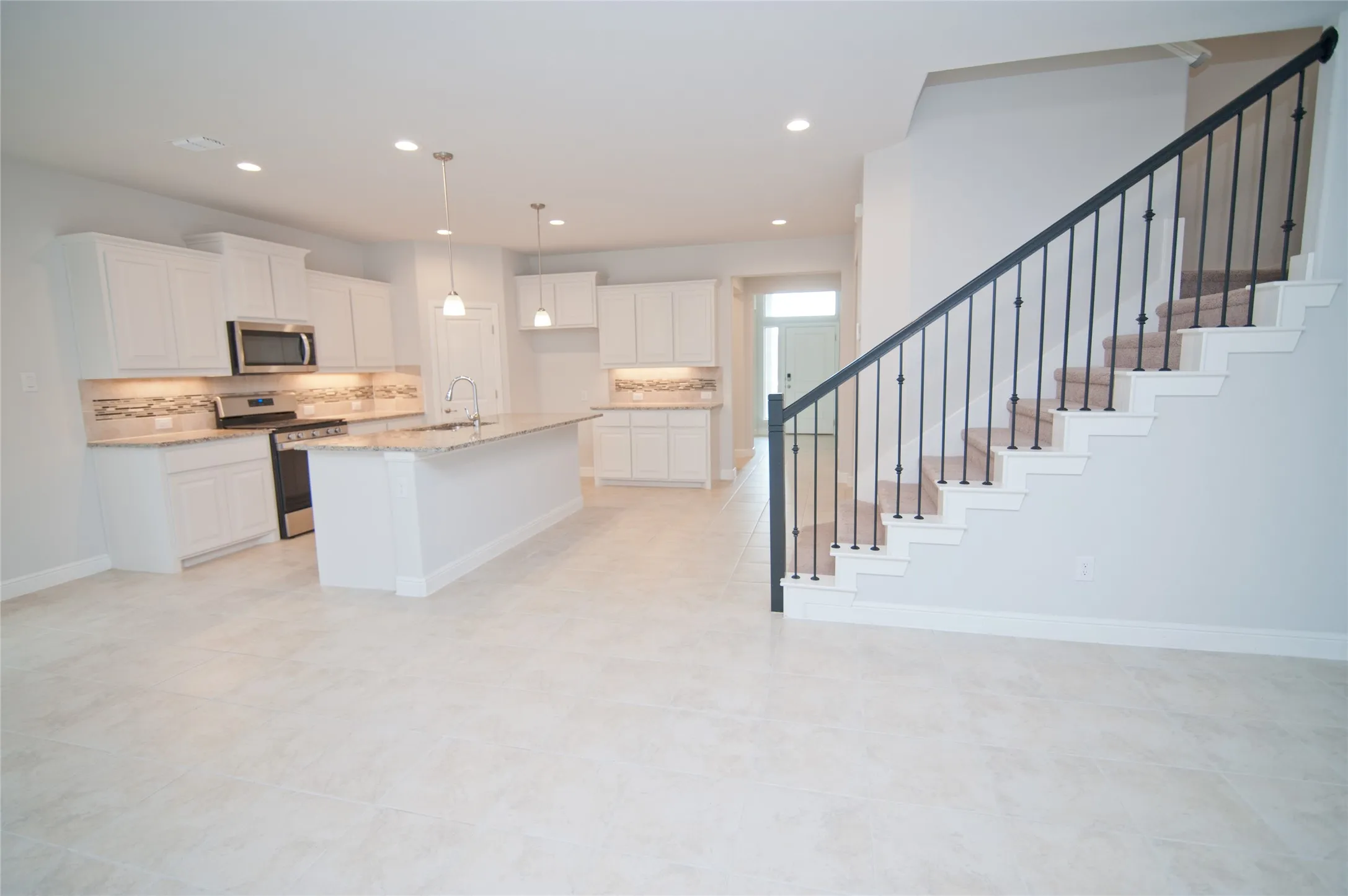 Open-concept kitchen featuring white cabinetry, granite countertops, and a tiled backsplash