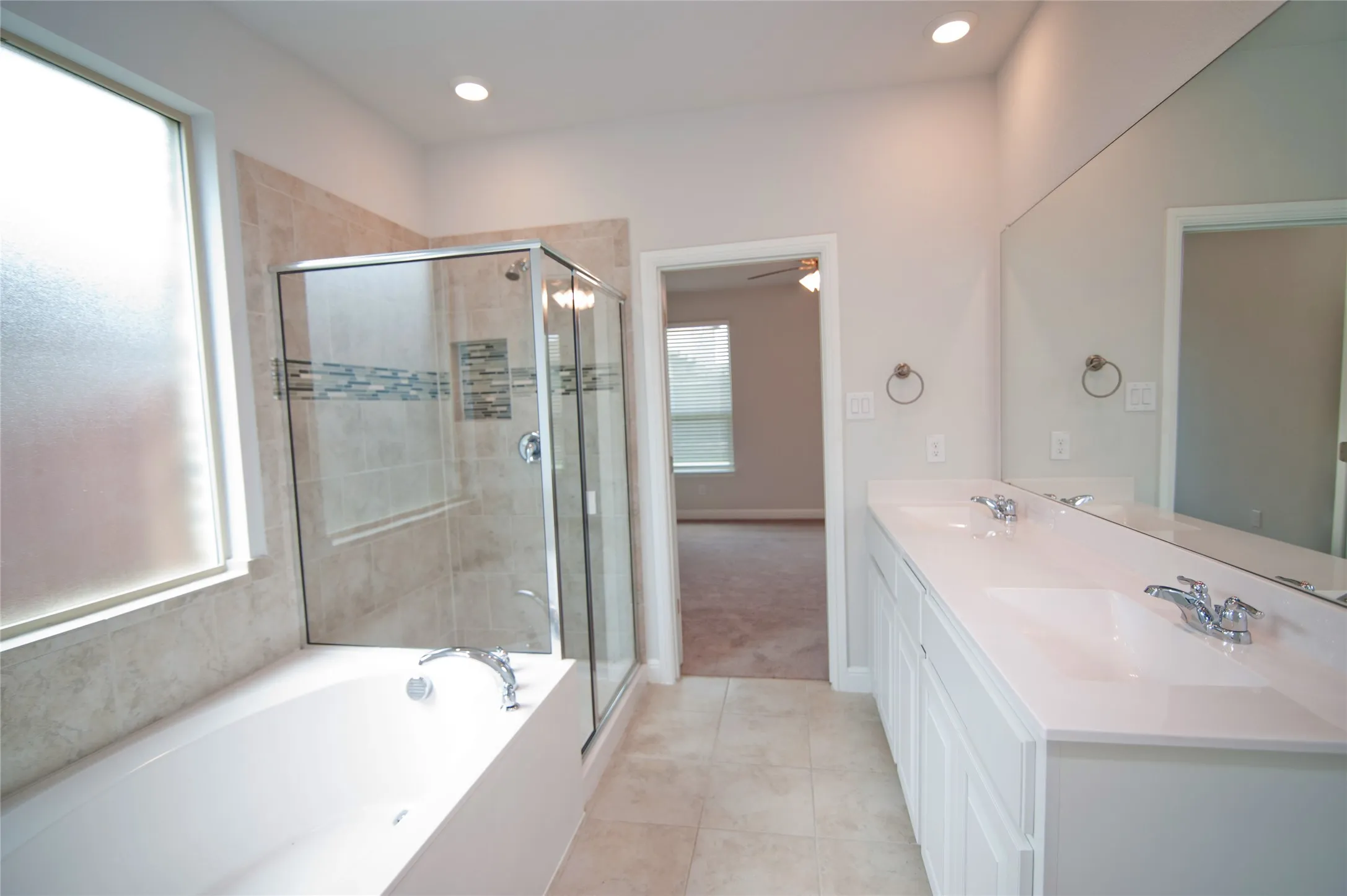 Double vanity with undermount sinks, a built-in tub, a glass-enclosed shower, tile flooring, and recessed lighting
