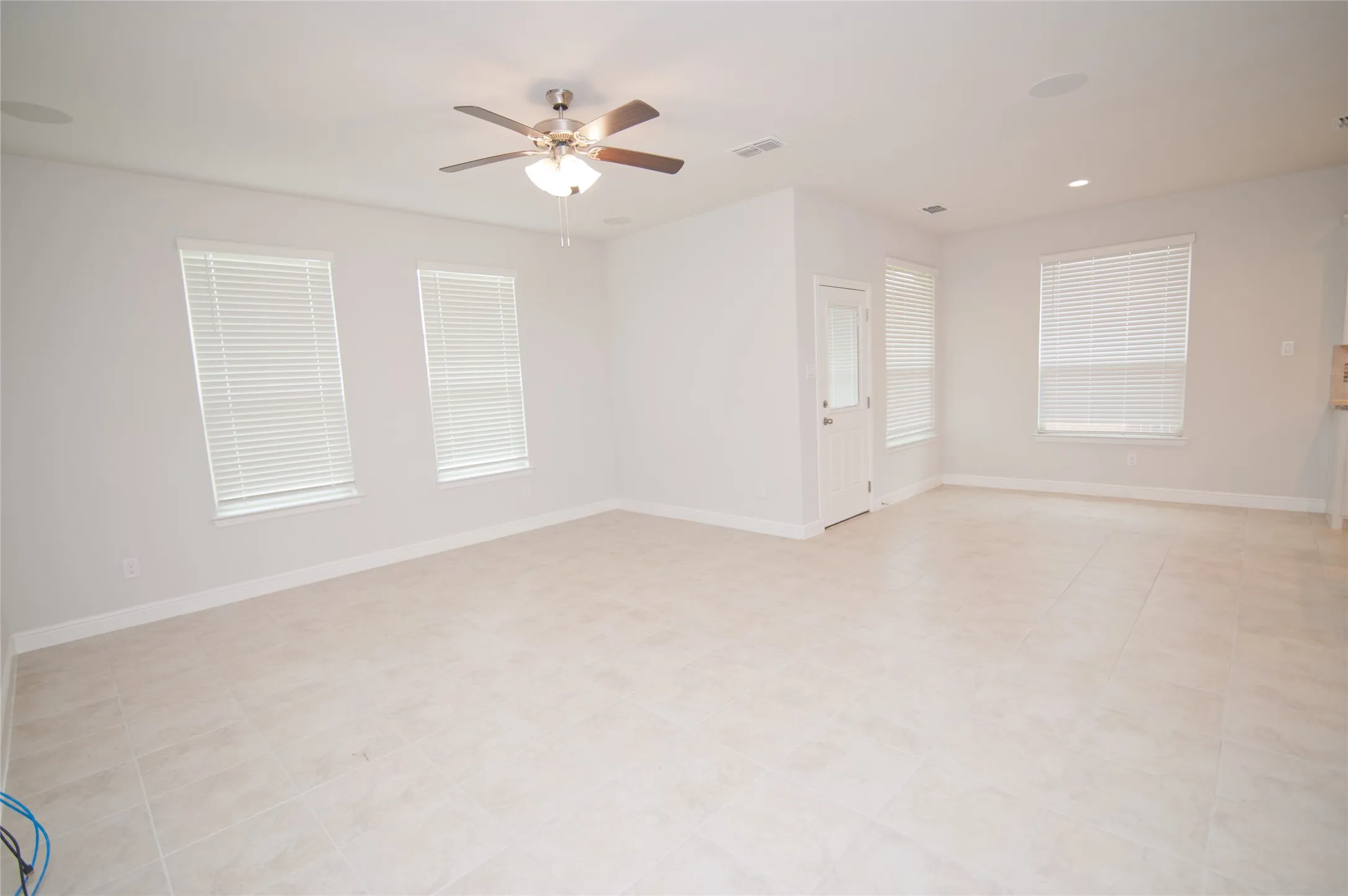 Expansive room featuring tile flooring, multiple windows with blinds, a ceiling fan with light, and recessed lighting