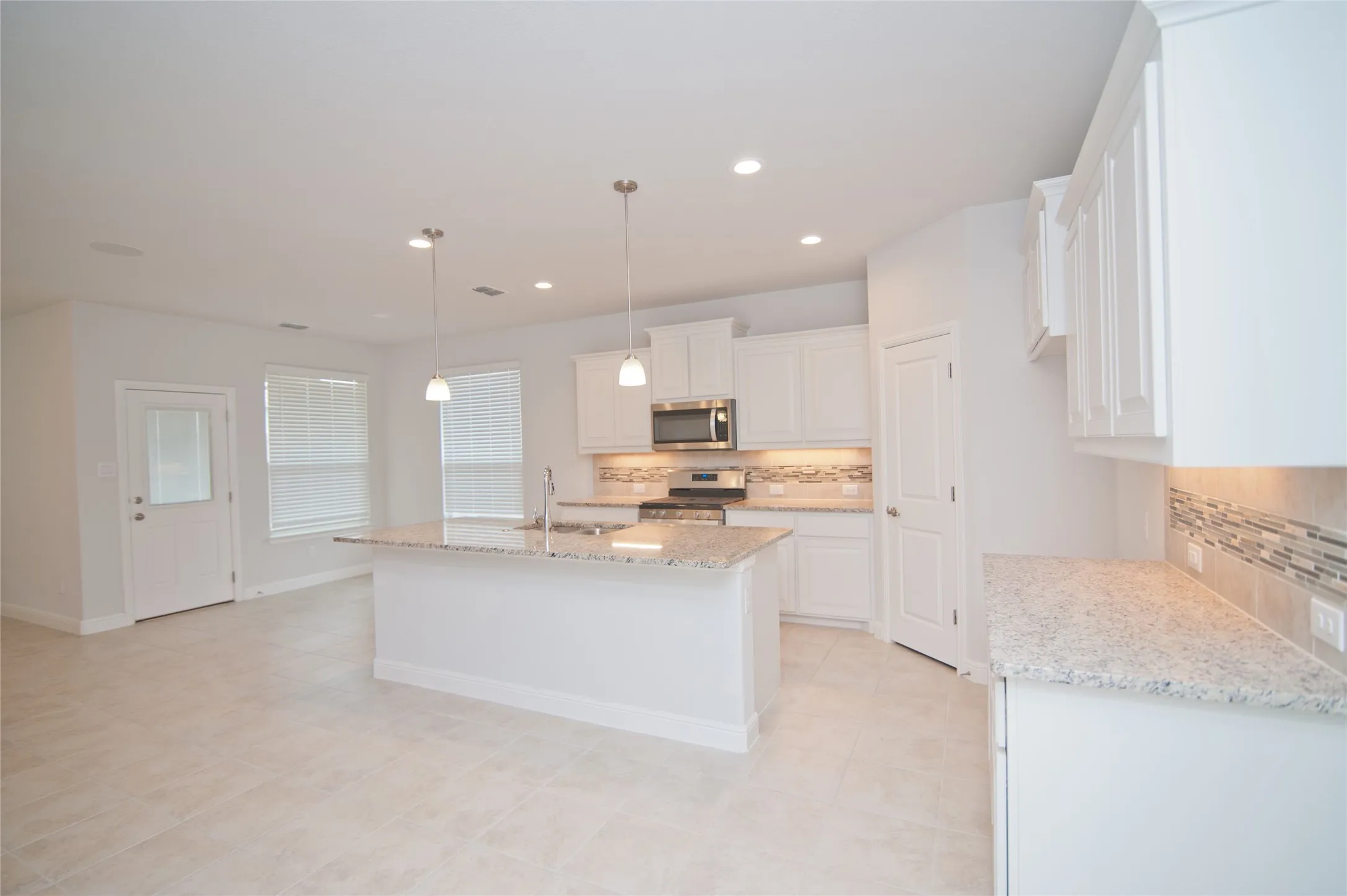 Open-concept kitchen featuring an eat-at island, granite countertops, white cabinetry, and stainless steel appliances