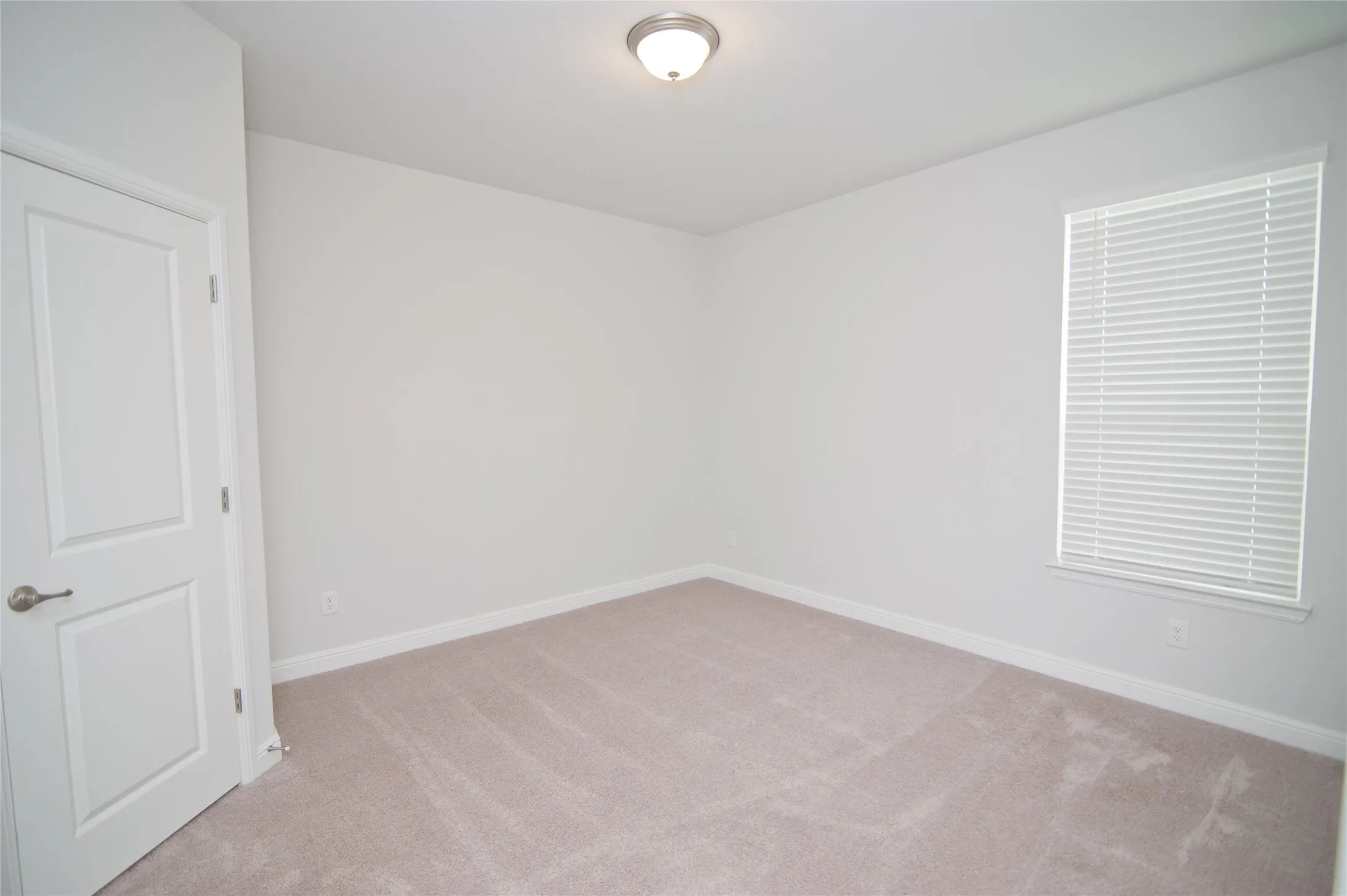 Neutral-toned carpeting, white walls, and a window with horizontal blinds