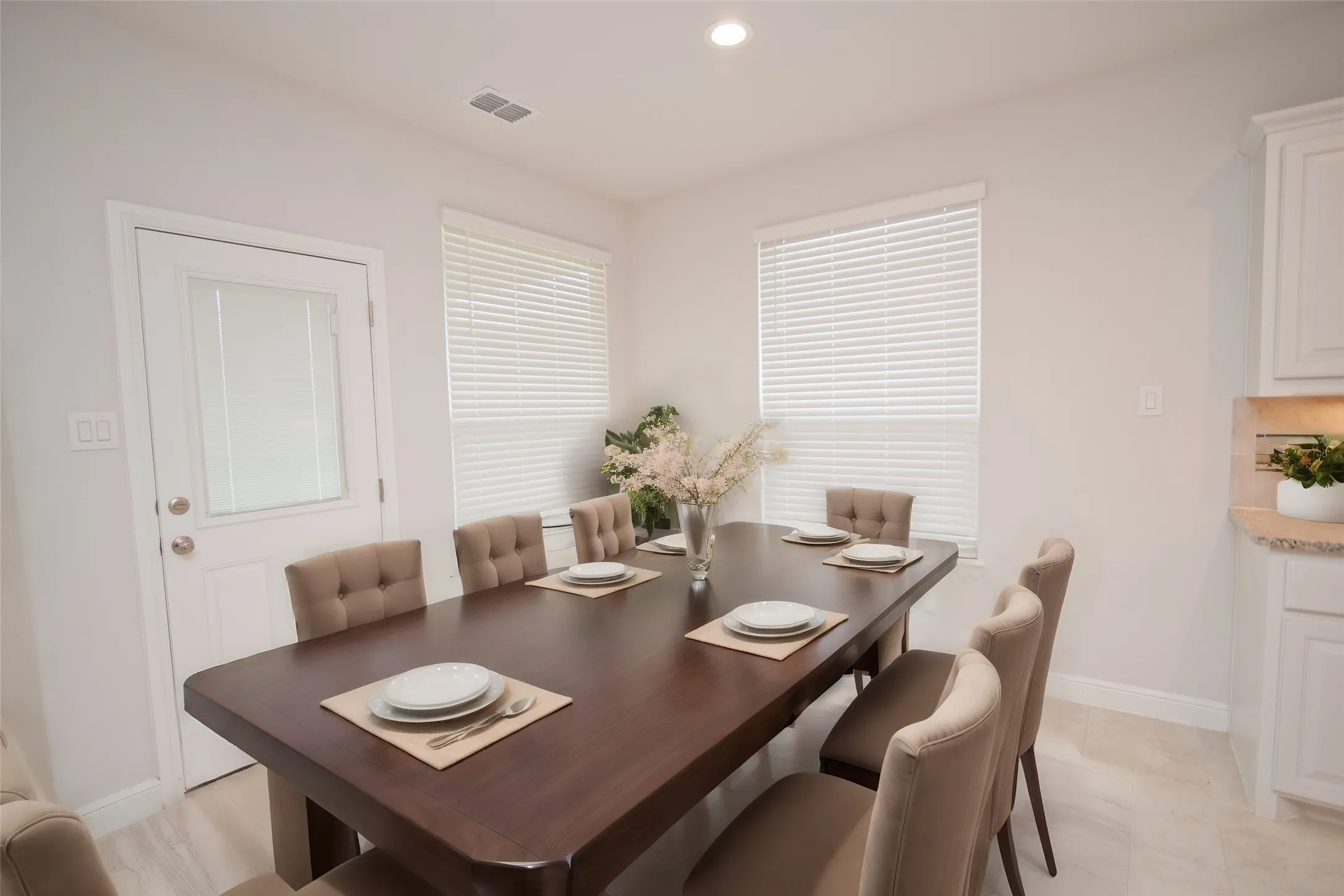 Bright dining space featuring a large window with blinds, recessed lighting, and tile flooring