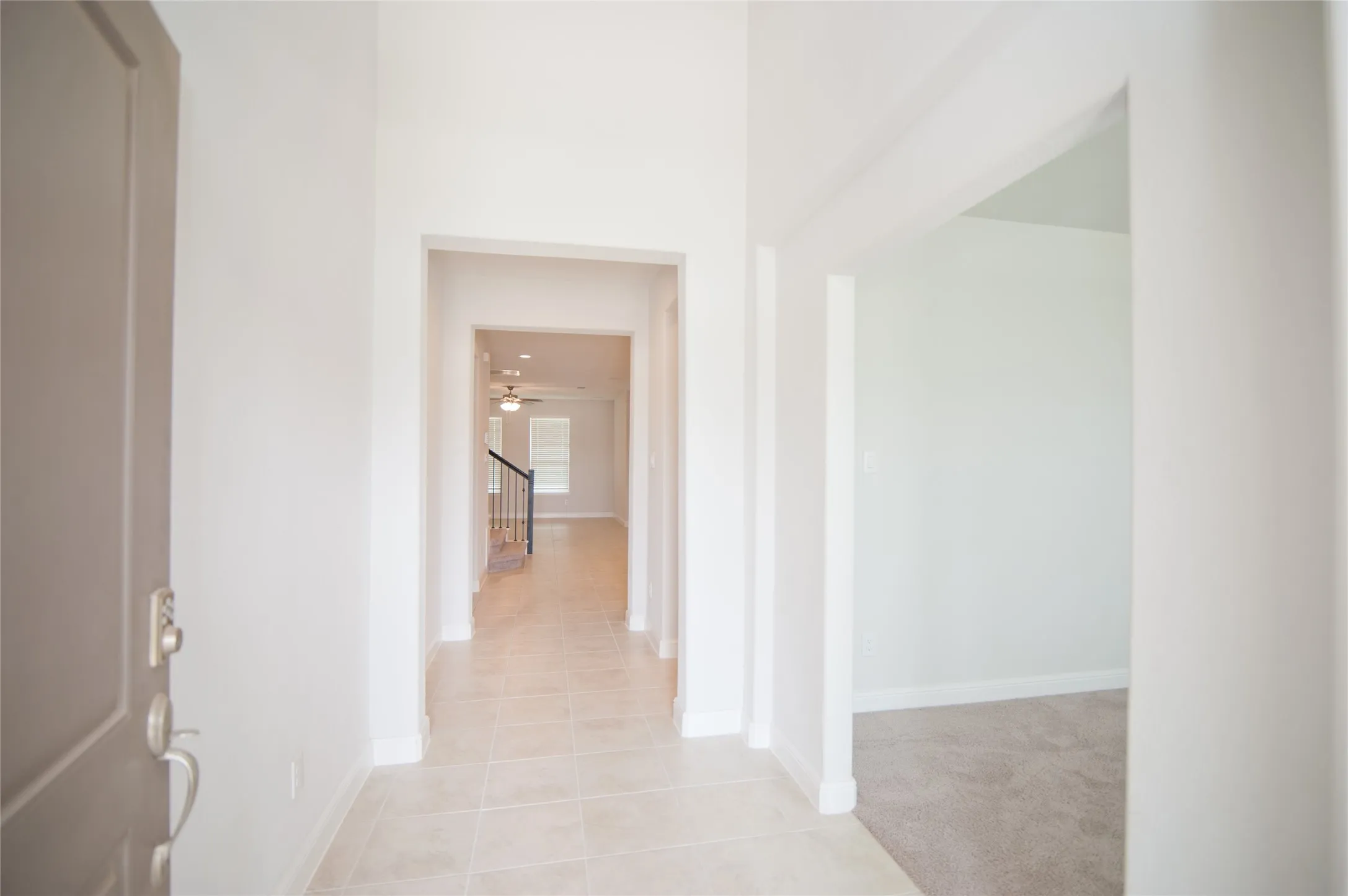 Entryway featuring a paneled door, tiled flooring, cased openings, and a staircase with a metal railing