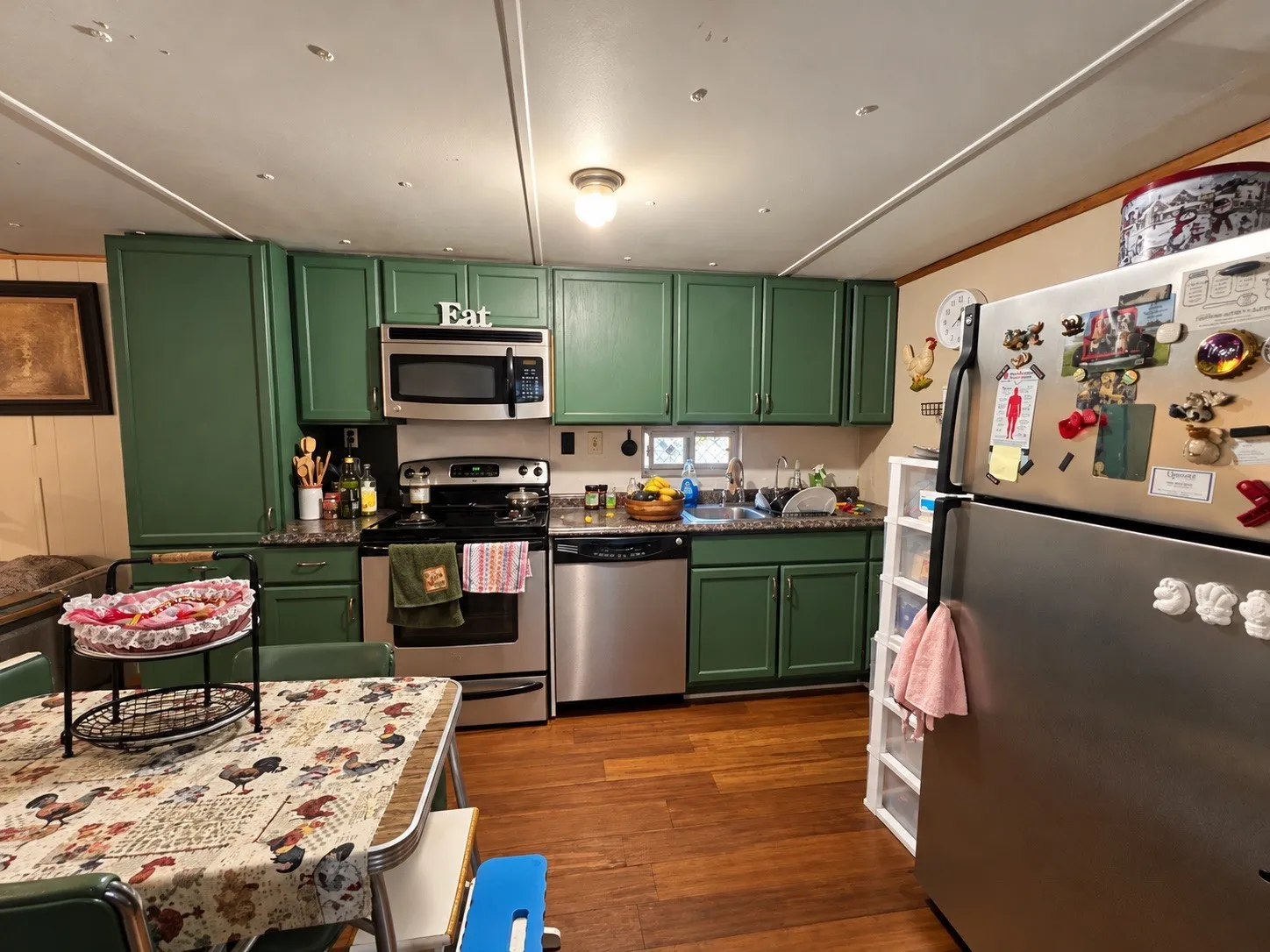 Kitchen featuring green painted cabinetry and wood-finish flooring
