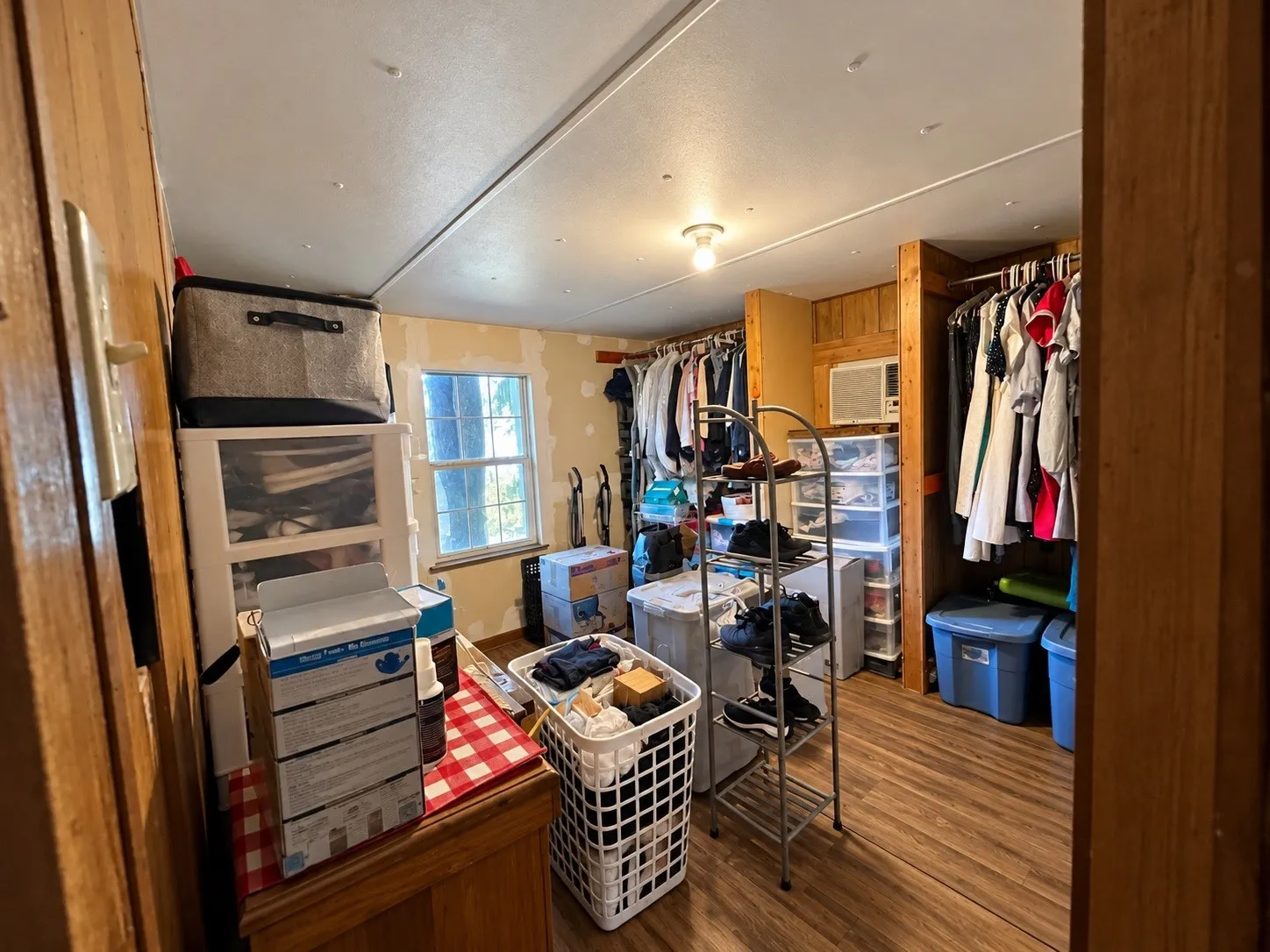 Wood-finish flooring with a window, ceiling light fixture, and built-in wood-paneled walls