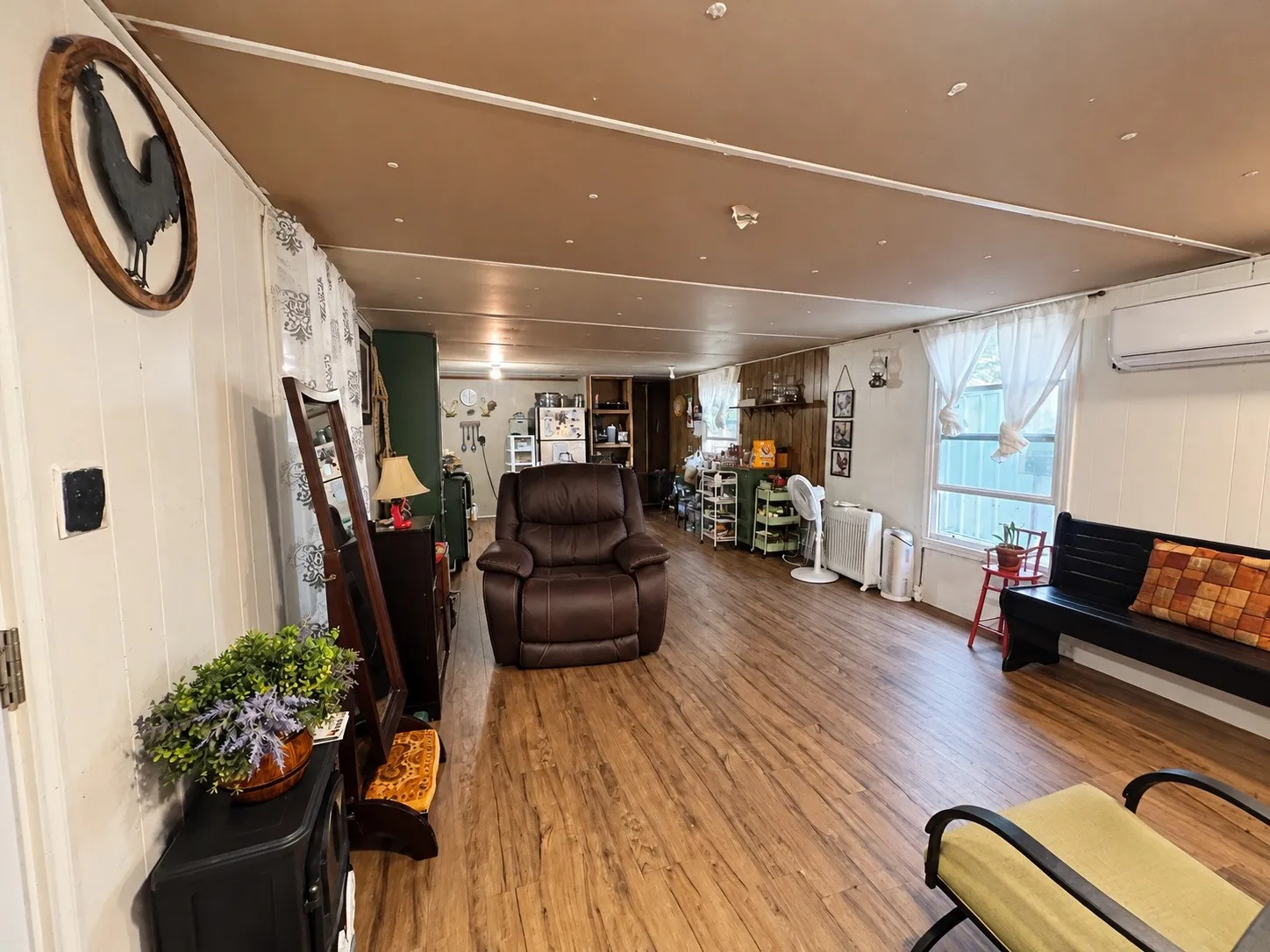 Wood-finish flooring throughout, white vertical paneling, and an exposed ceiling beam