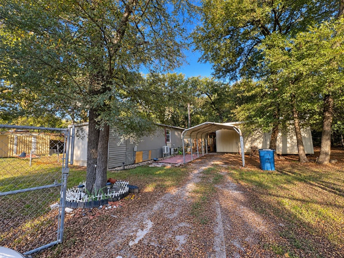 Gravel driveway leading to a covered carport