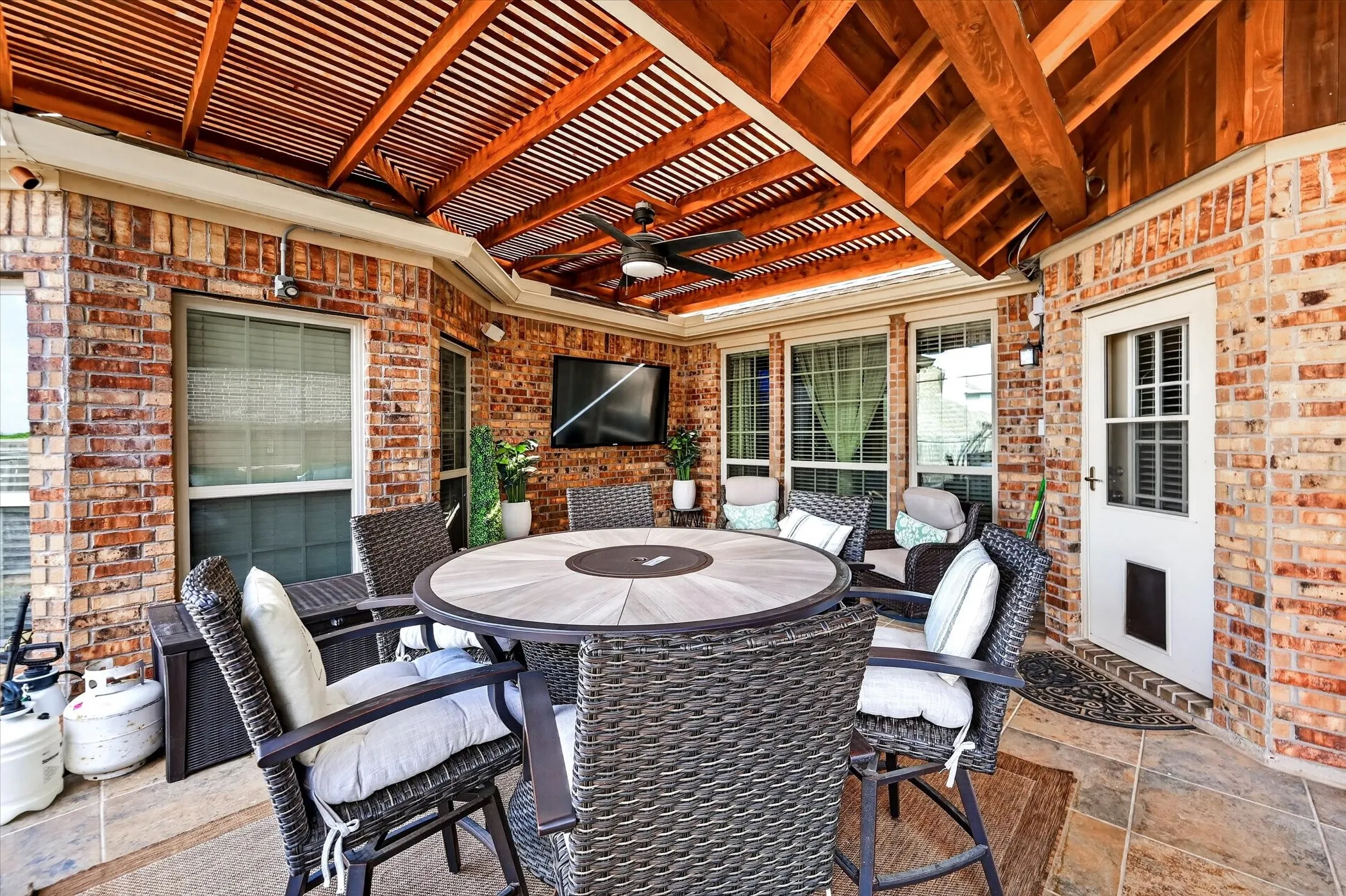 Brick exterior featuring a wood slat ceiling, exposed wood beams, ceiling fan, and tiled flooring