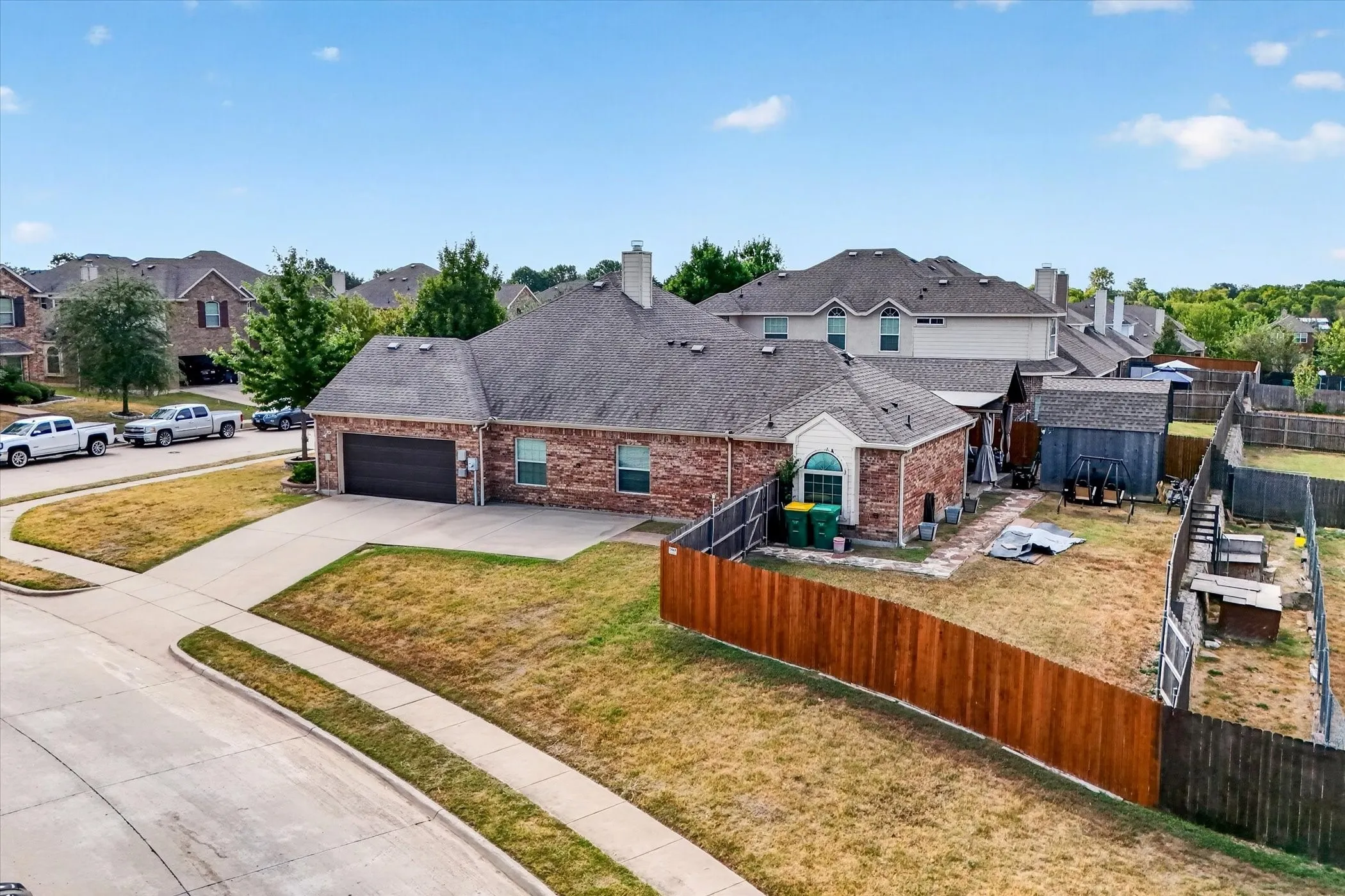 Brick exterior with arched window, attached two-car garage, and fenced backyard