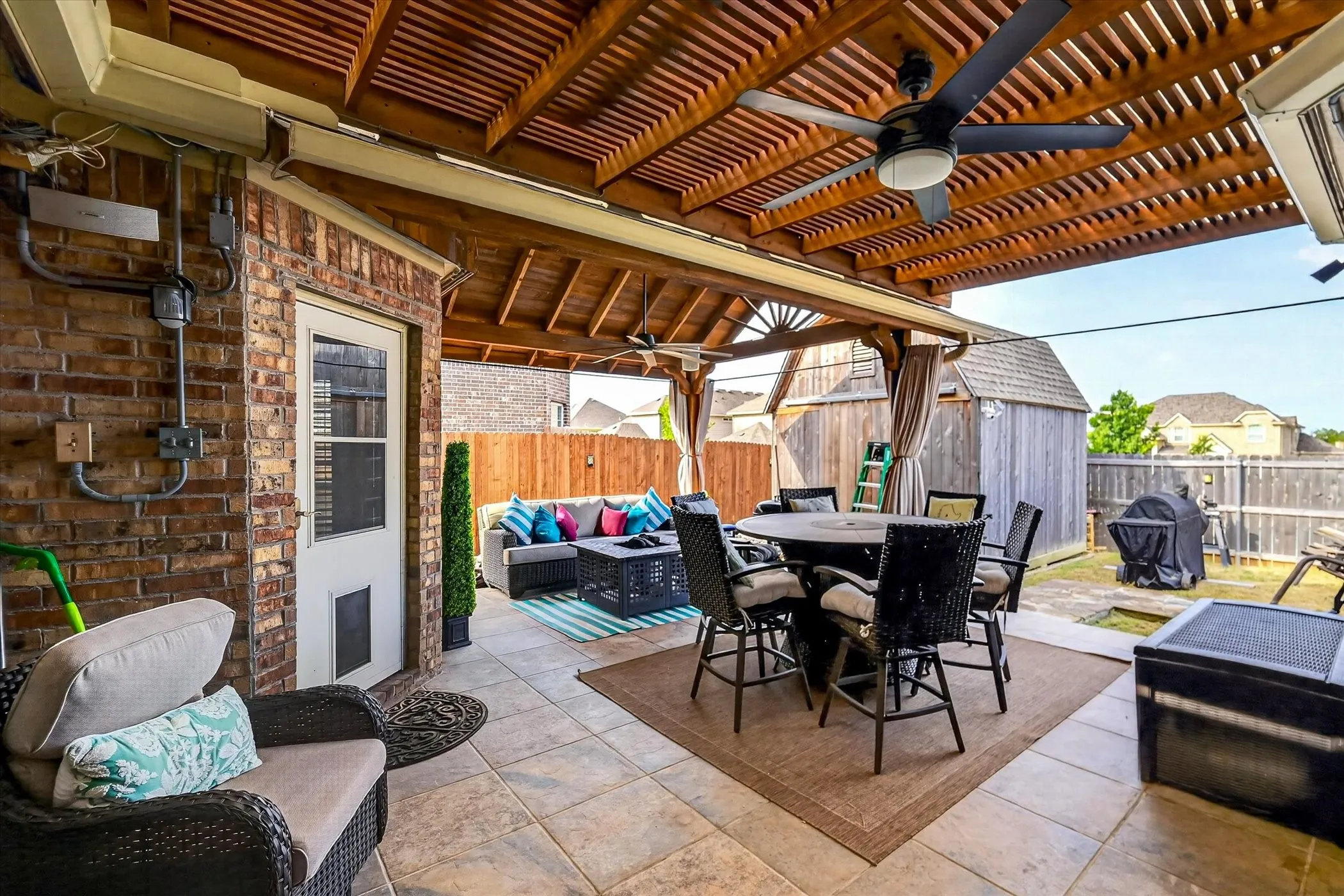 Covered patio featuring a wood-slat ceiling, dual ceiling fans, and tiled flooring
