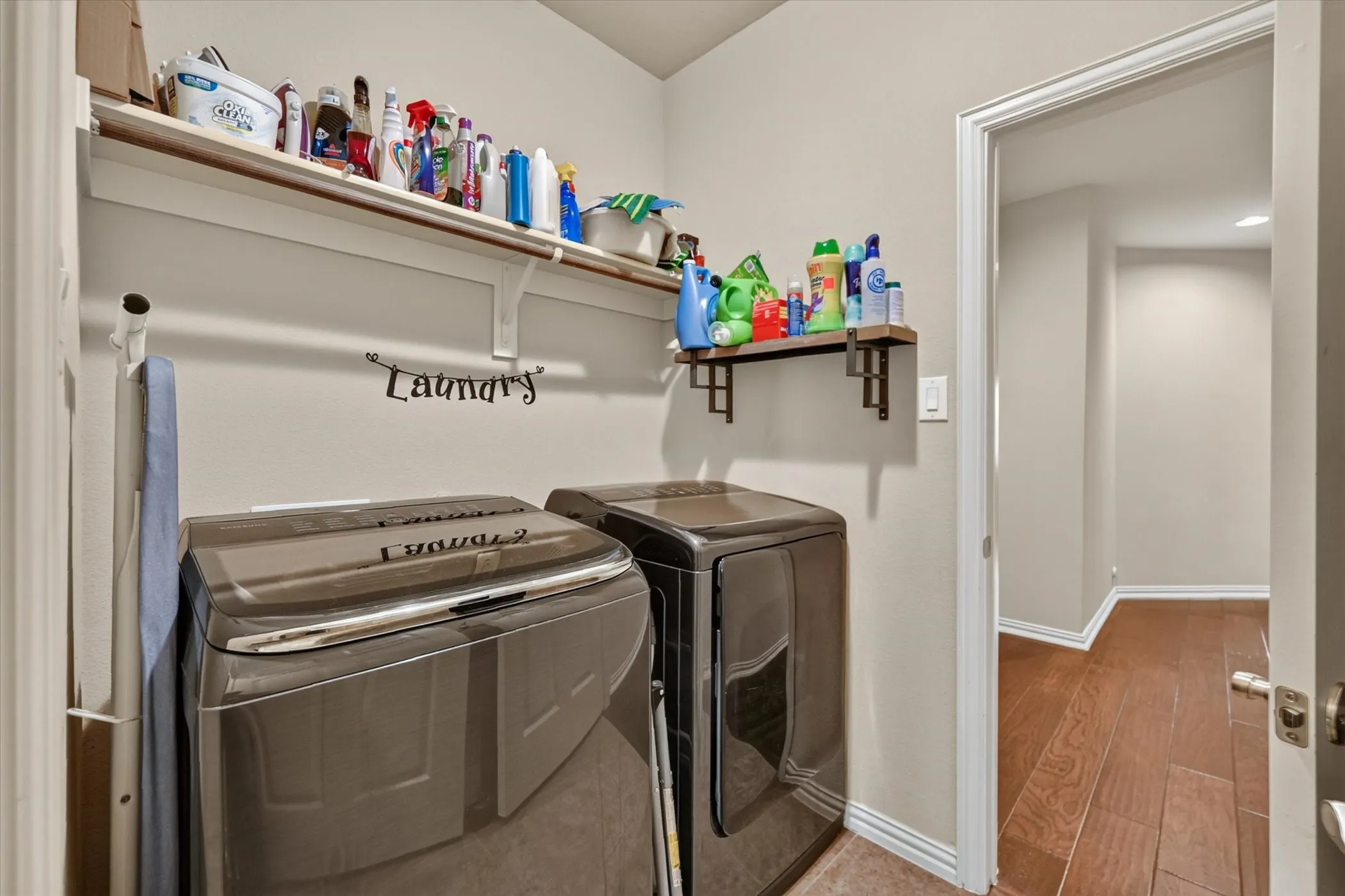 Spacious utility area featuring a built-in shelf, additional wall-mounted shelving, and wood-finish flooring