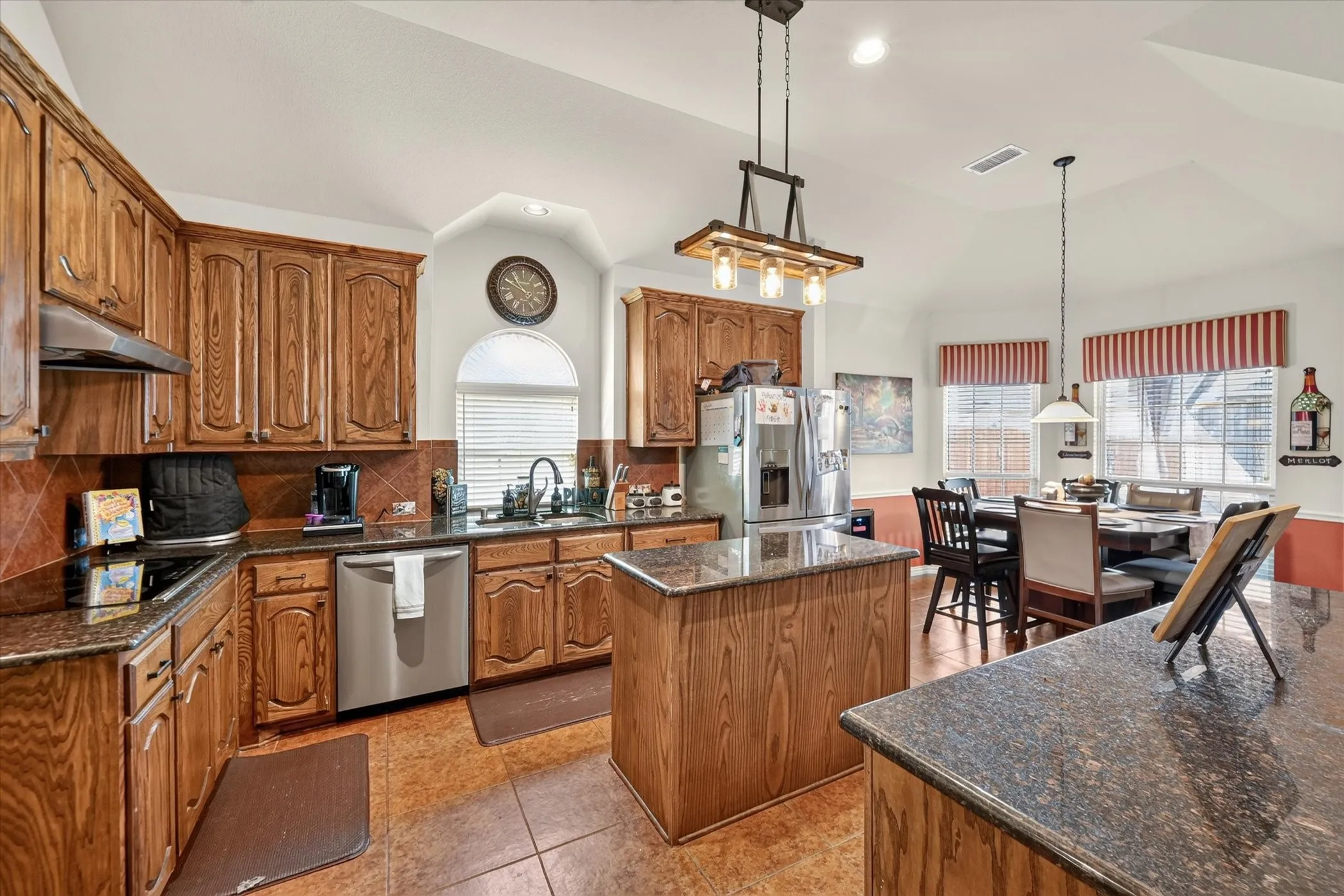 Kitchen featuring wood cabinetry, dark countertops, a central island, and stainless steel appliances