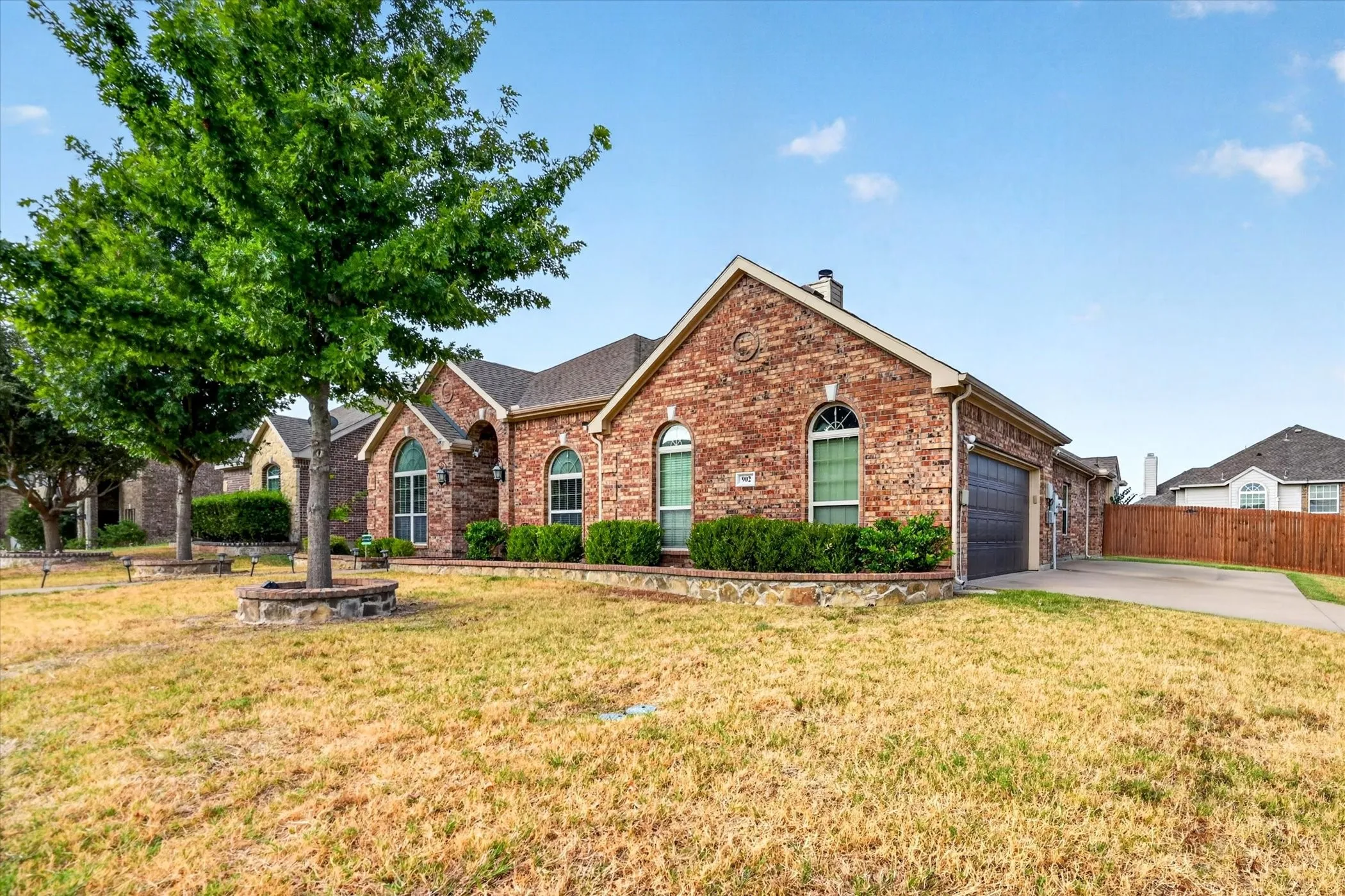 Brick exterior with arched windows, an attached garage, and a concrete driveway
