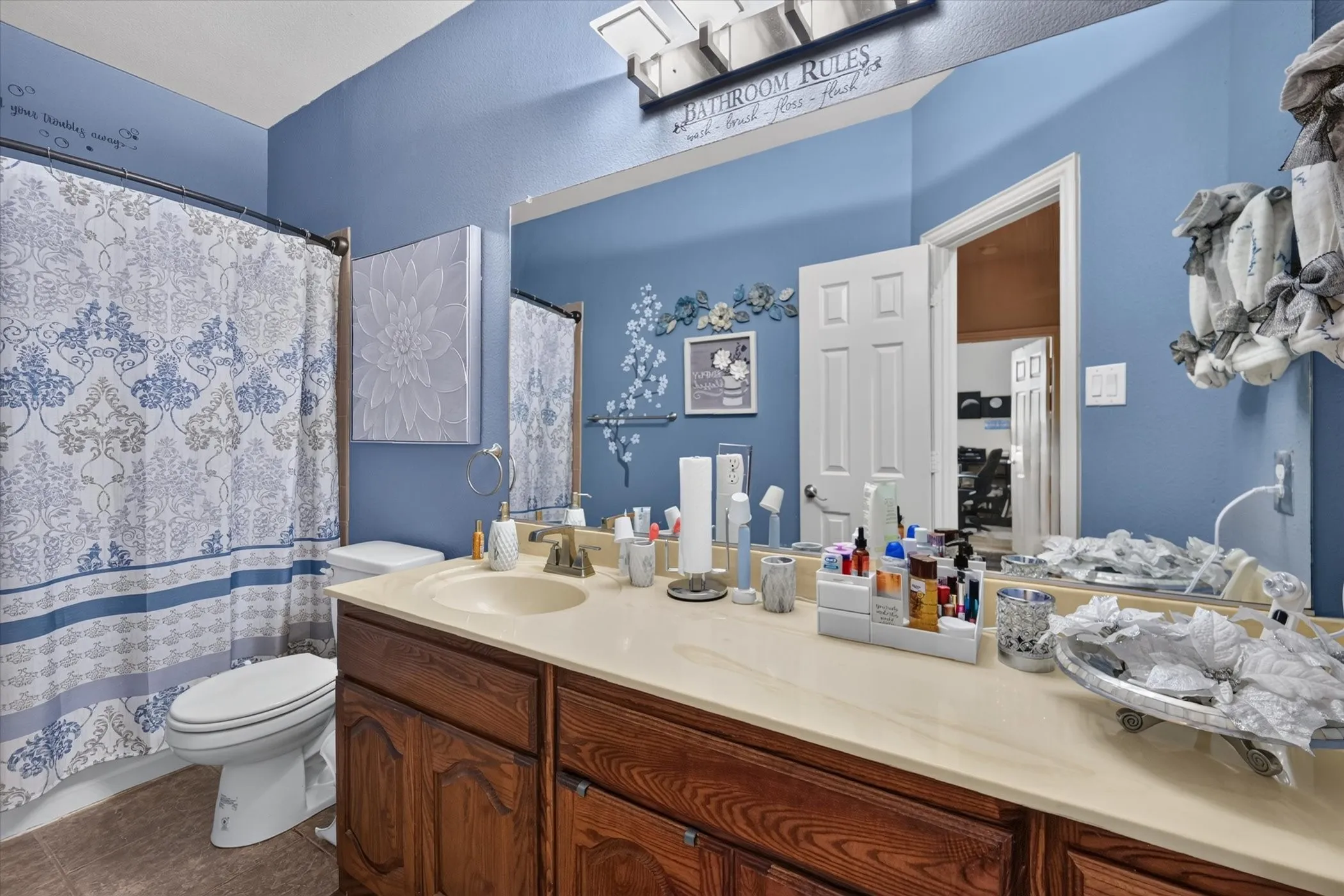 Single vanity with an integrated sink, wood-finish cabinetry, and a full-width wall mirror