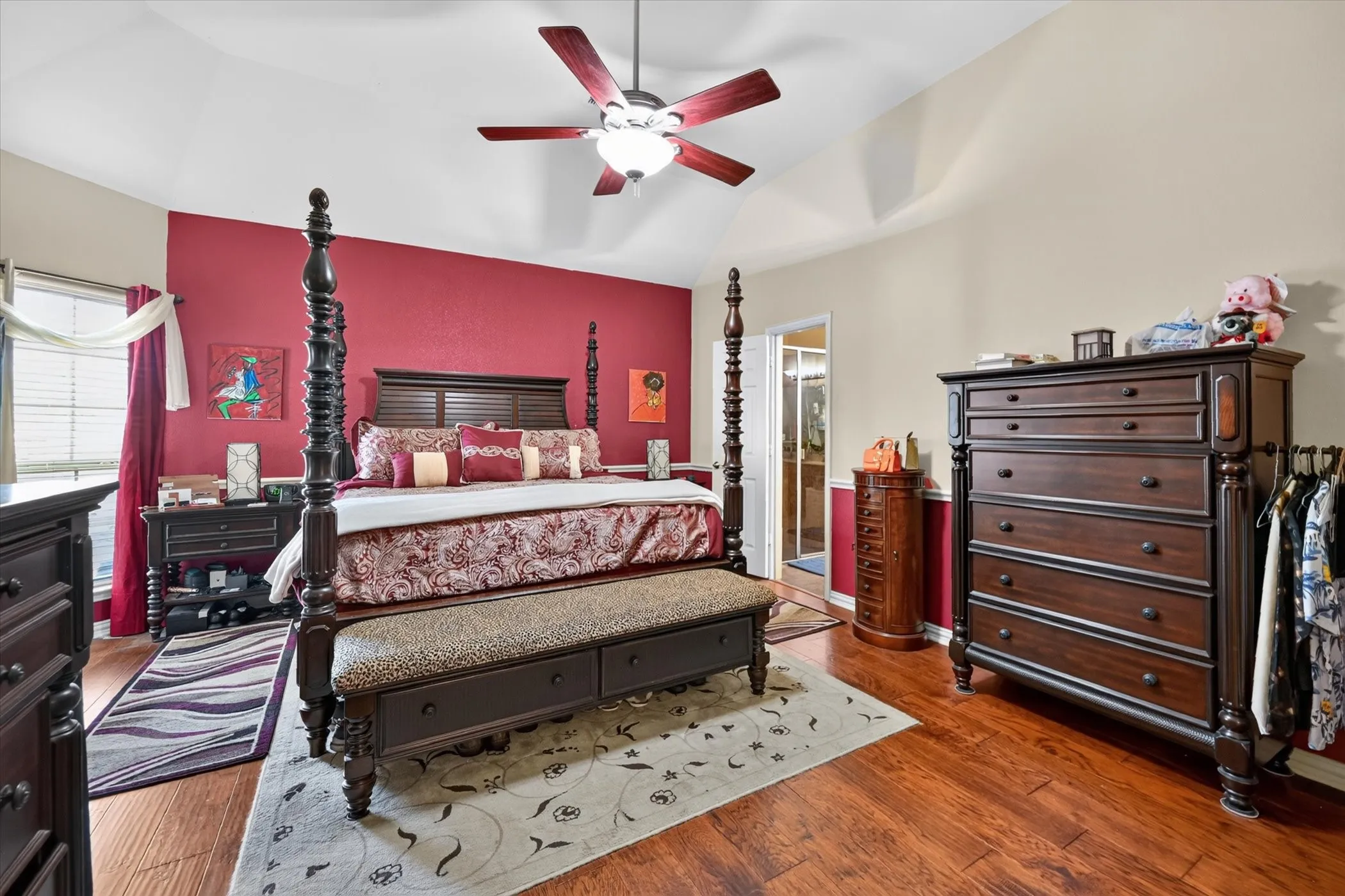 Vaulted ceiling with a ceiling fan, hardwood flooring, and a window with blinds