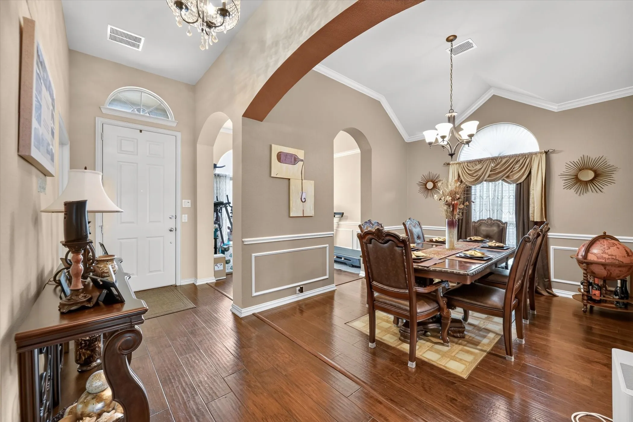 Hardwood flooring, vaulted ceiling, arched doorways, crown molding, and wainscoting