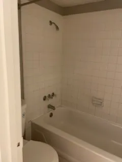 White tile shower surround with a built-in tub and shower fixture